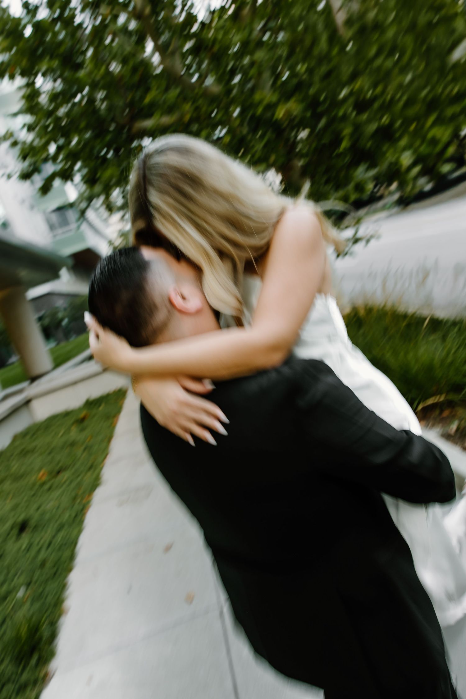 Couple sharing a joyful embrace outdoors with trees in the background.