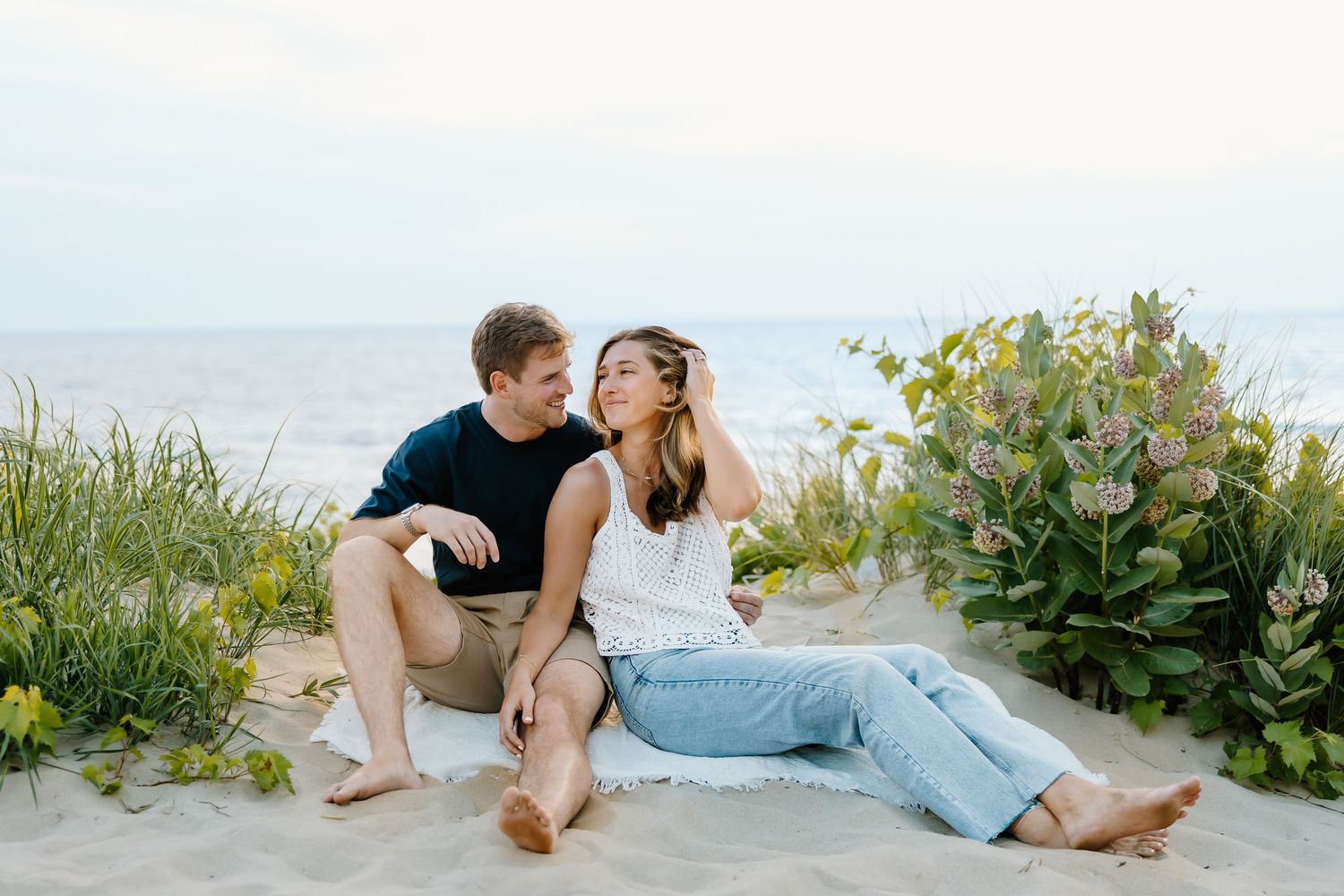 Intimate beach photography session with couple resting on sandy shore.