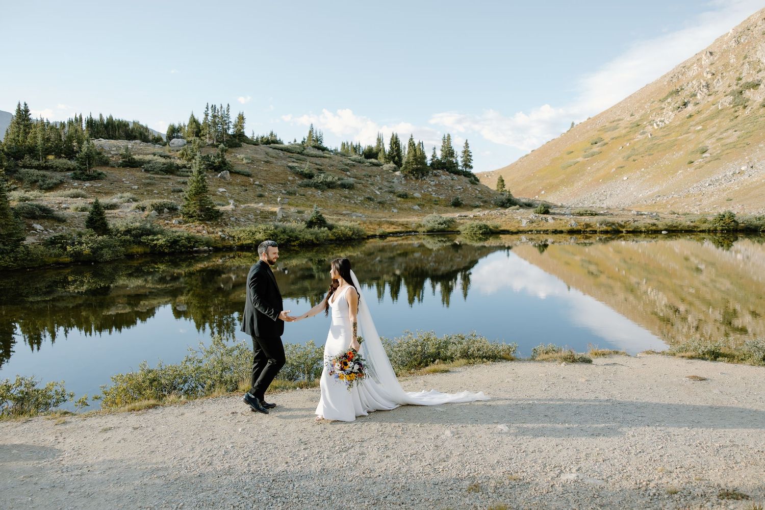 Wedding photography session by an alpine lake with snow-capped mountains in the background.
