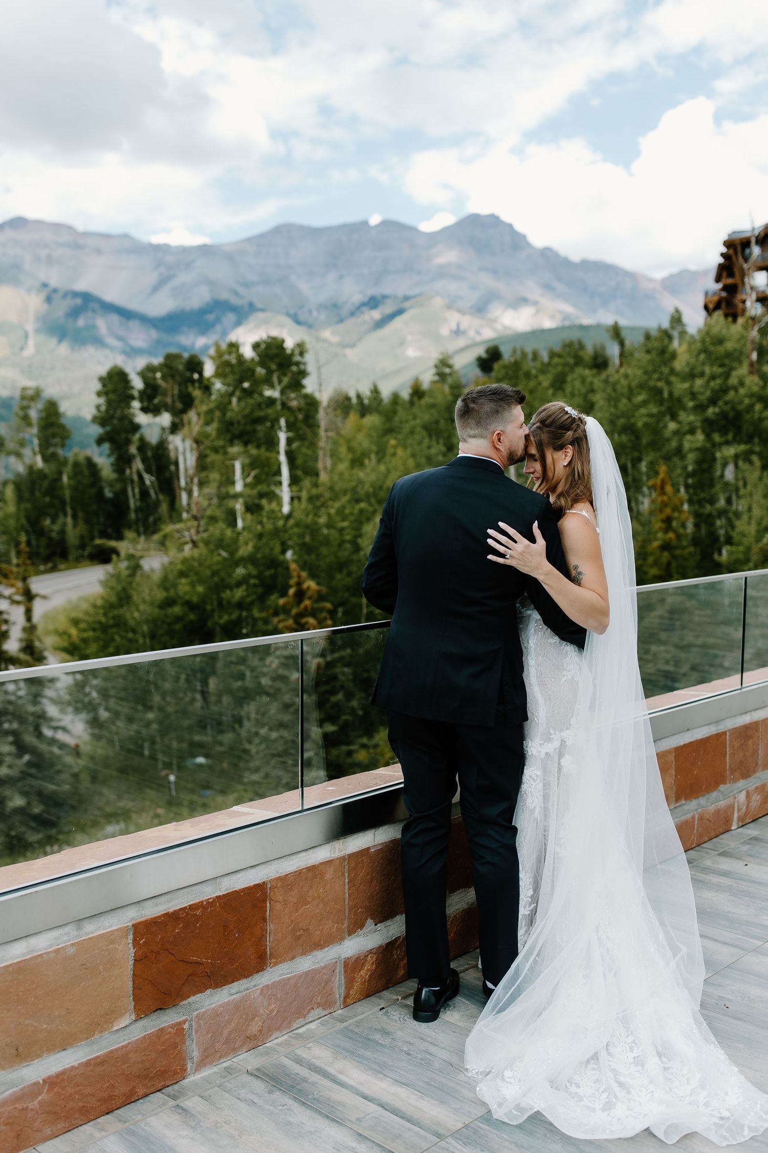 A romantic wedding moment captured on a terrace overlooking snow-capped mountains.
