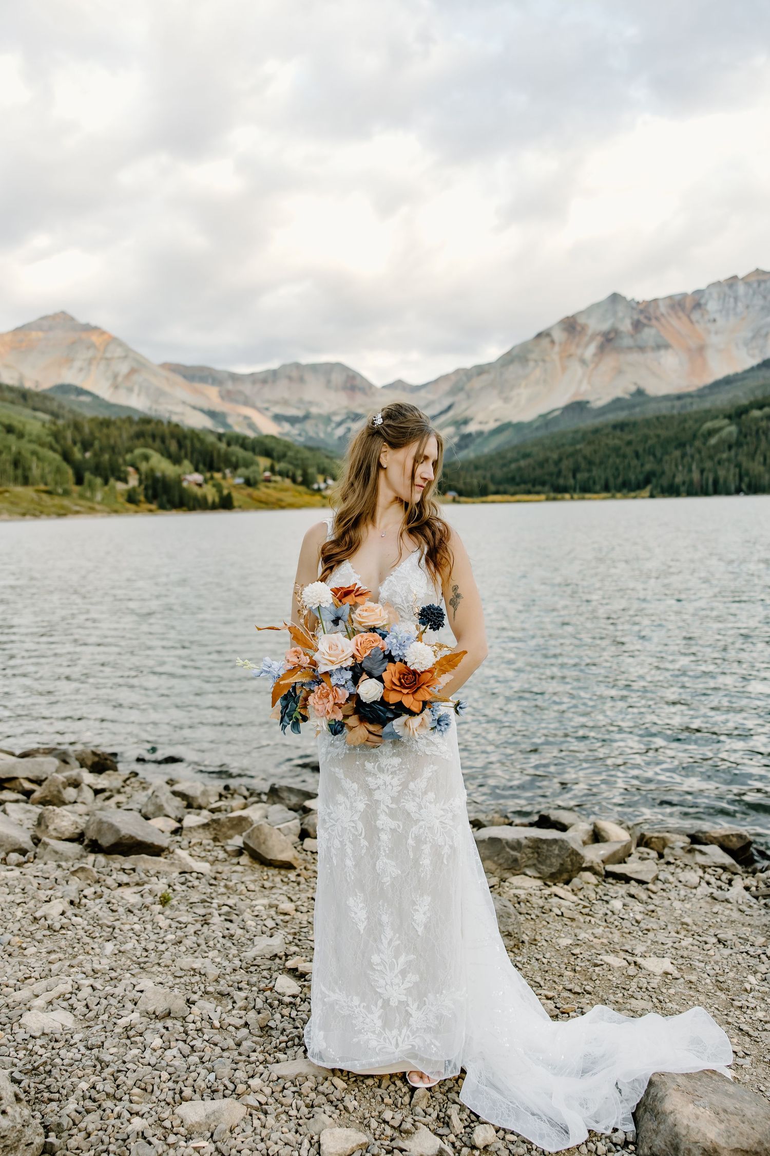 Scenic mountain lake setting with rocky shore and cloudy sky backdrop.