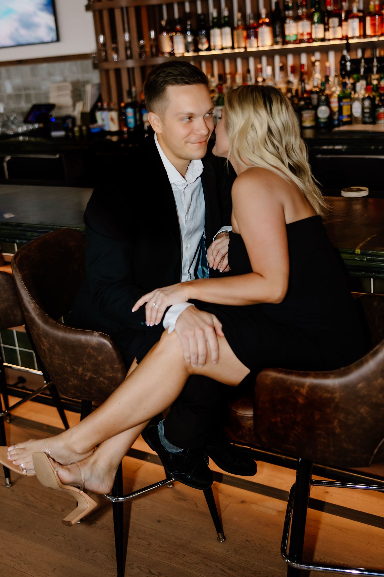 Romantic couple sitting at an upscale bar with intimate lighting.