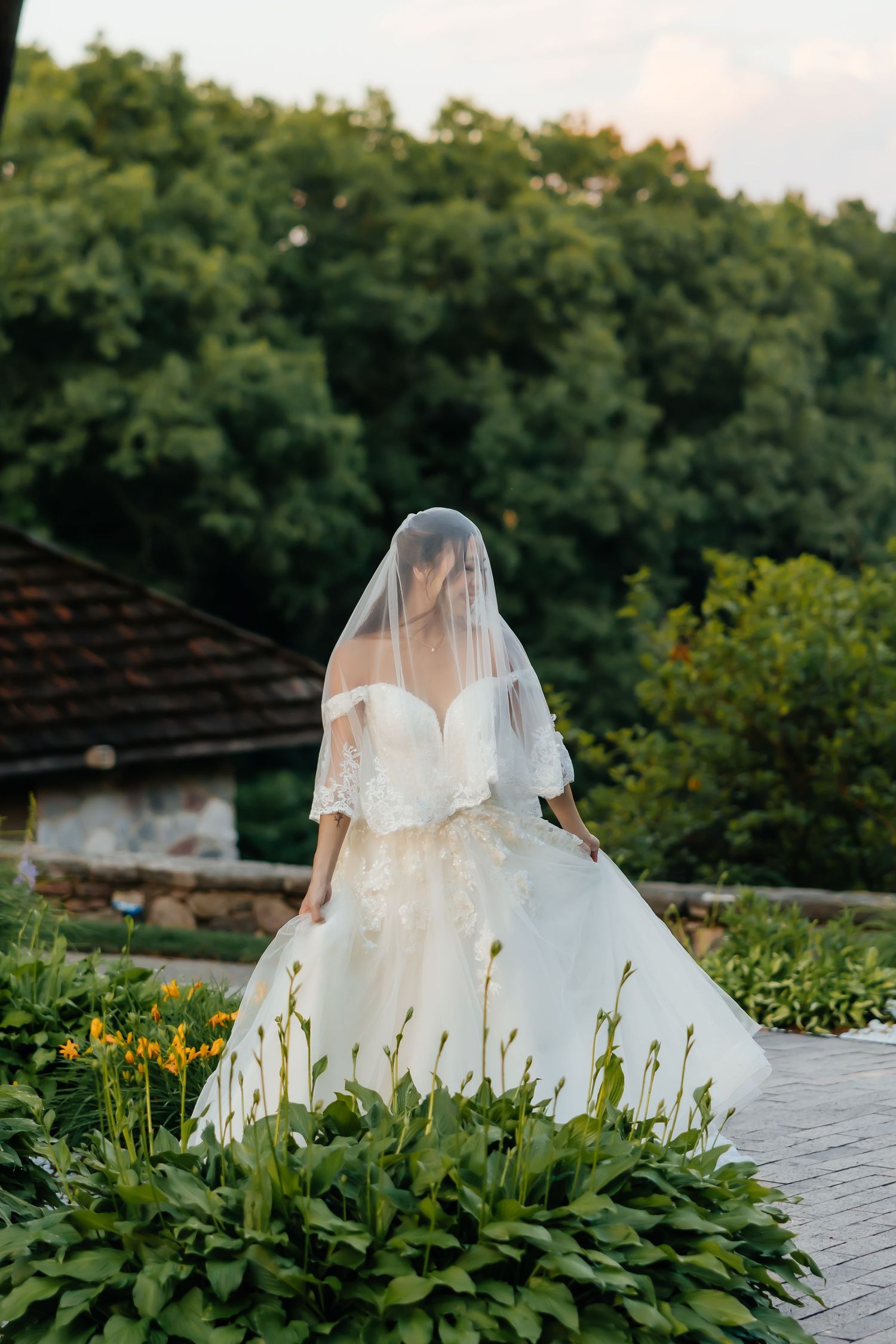 White wedding dress photographed in garden setting with lush greenery.