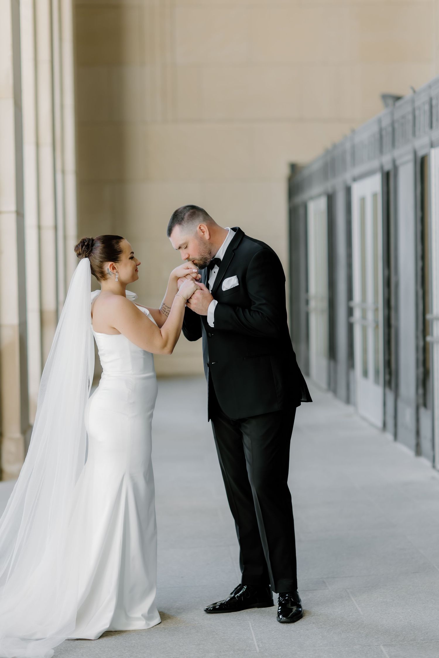 A romantic wedding moment shared in an elegant colonnade with natural lighting.