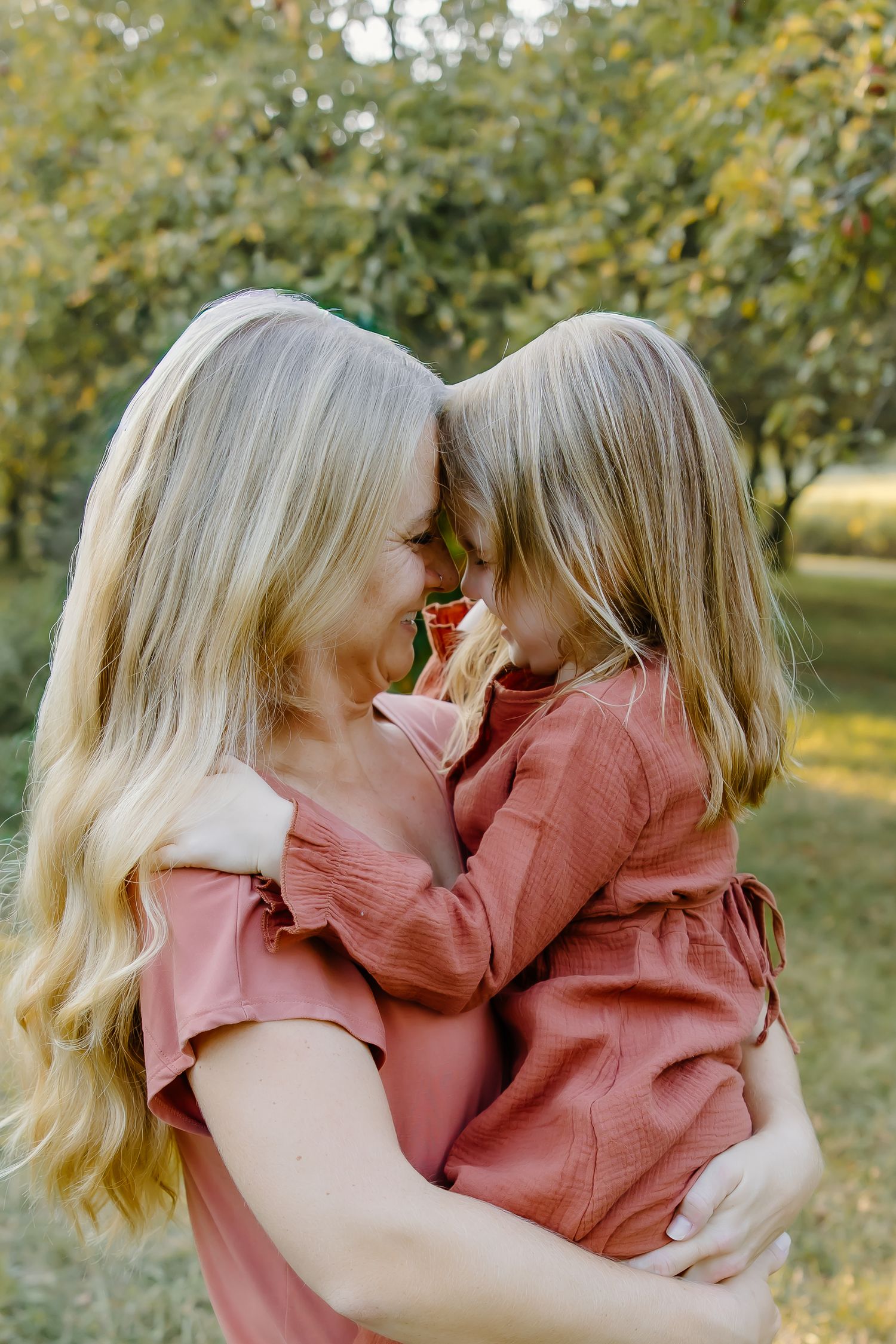 Playful moments between family members hugging and laughing together in a sunlit outdoor setting.