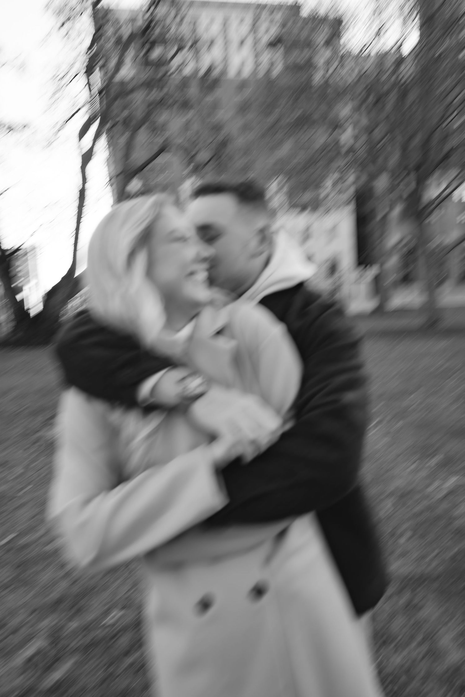 Blurred black and white motion photo of two people dancing outdoors.