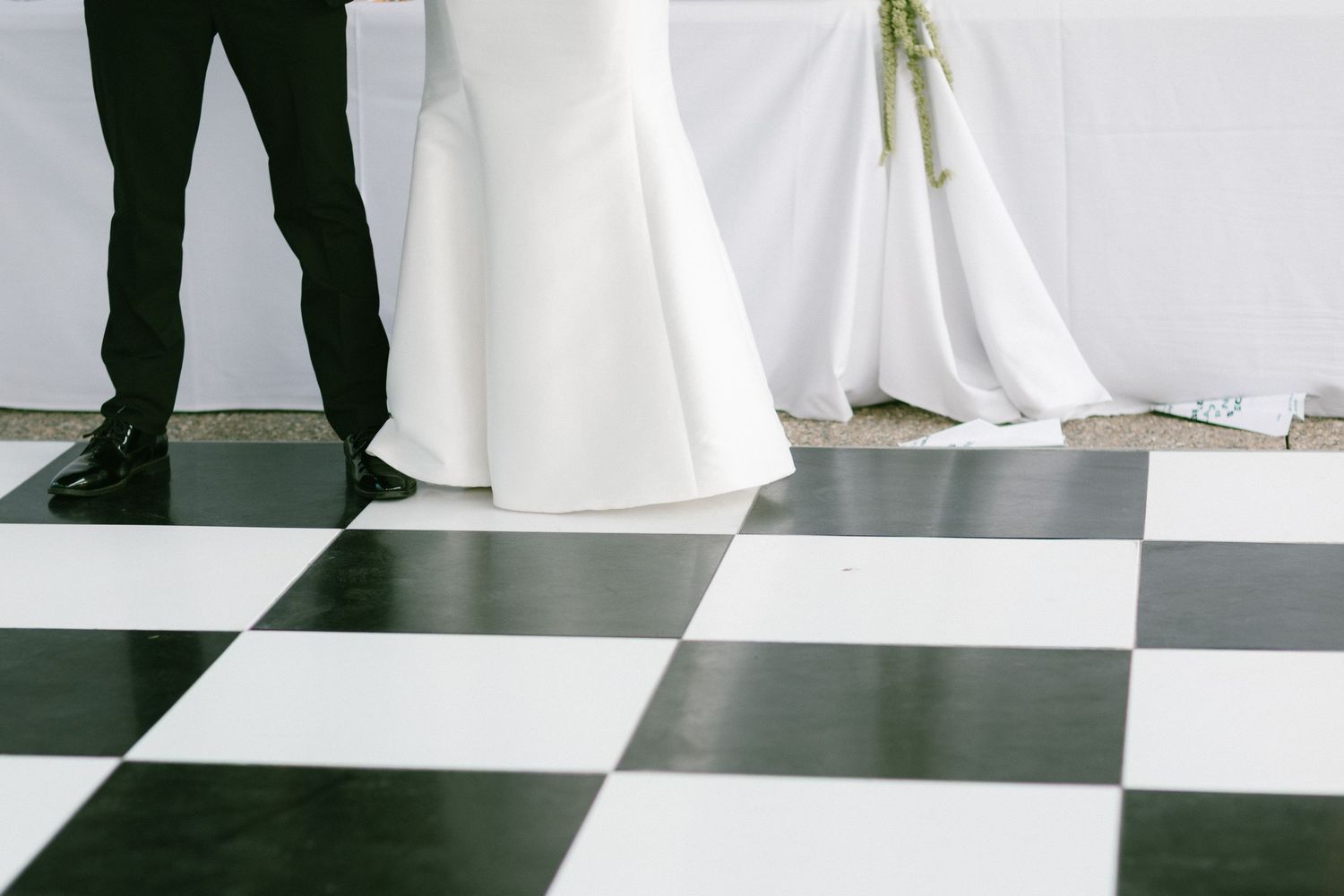 Minimalist wedding photo with black and white checkered floor and flowing bridal gown.