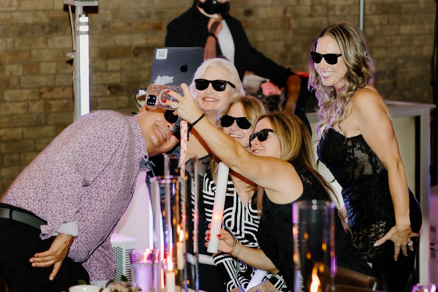 Wedding guests dancing with sunglasses at night reception party.