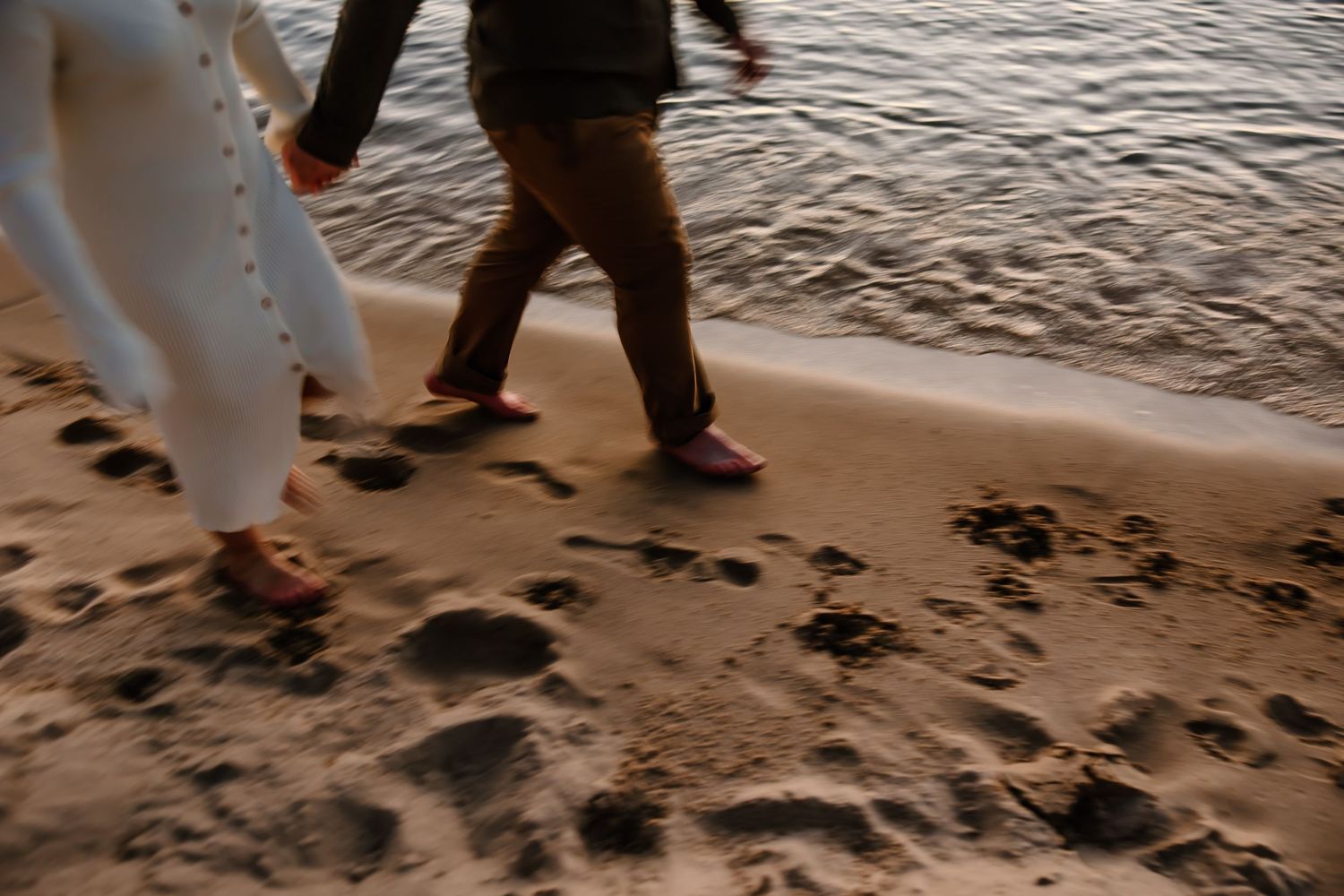 Footprints in wet sand along shoreline during sunset beach photoshoot.