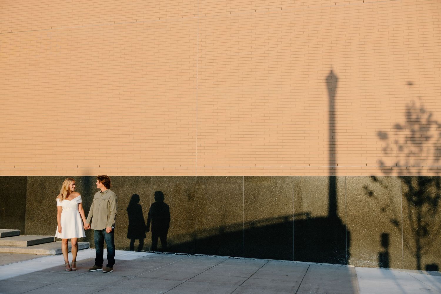 Long shadows cast on beige wall during sunset engagement session.