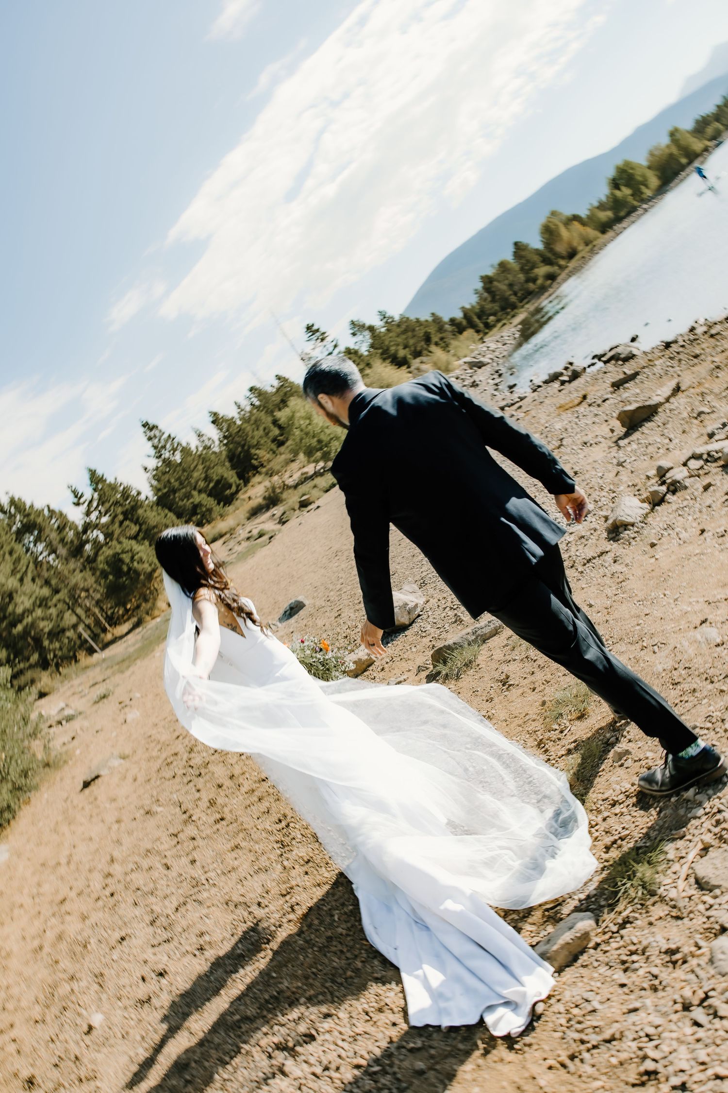 White flowing fabric catches wind on rocky mountain shoreline.