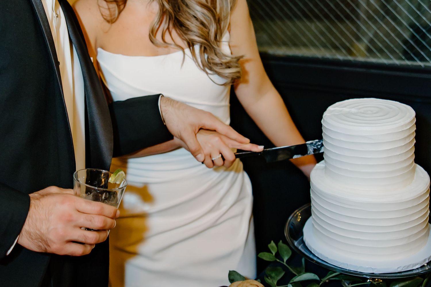 Close-up of wedding cake cutting with elegant white tiered design.