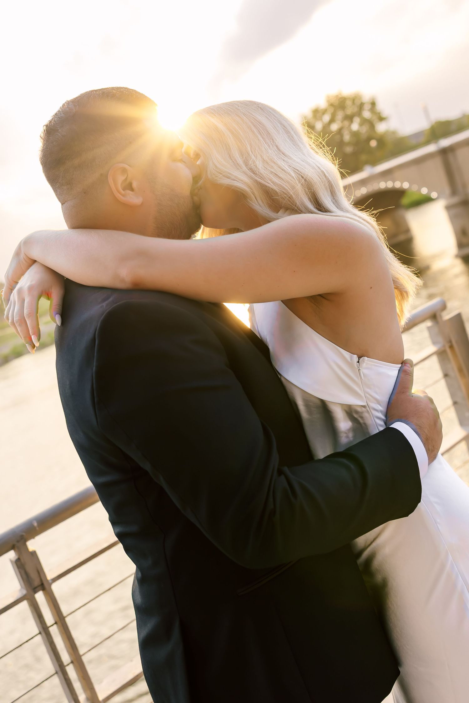 Romantic couple embraces on stone steps during golden hour sunset.