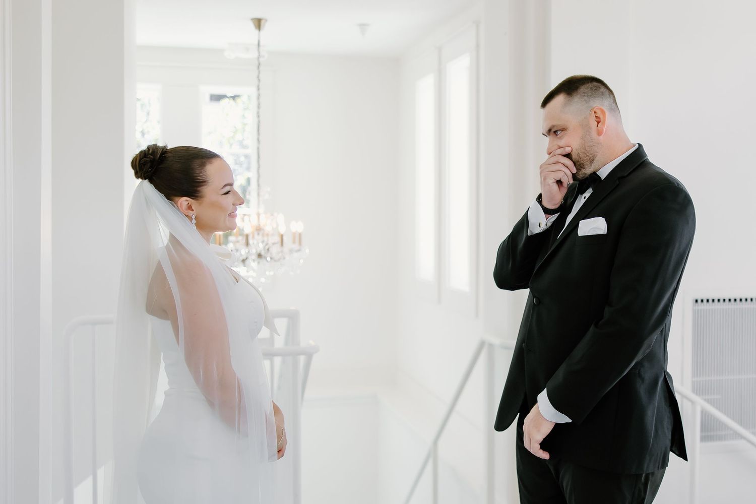 An elegant wedding moment captured in a bright white room with classic architectural details.
