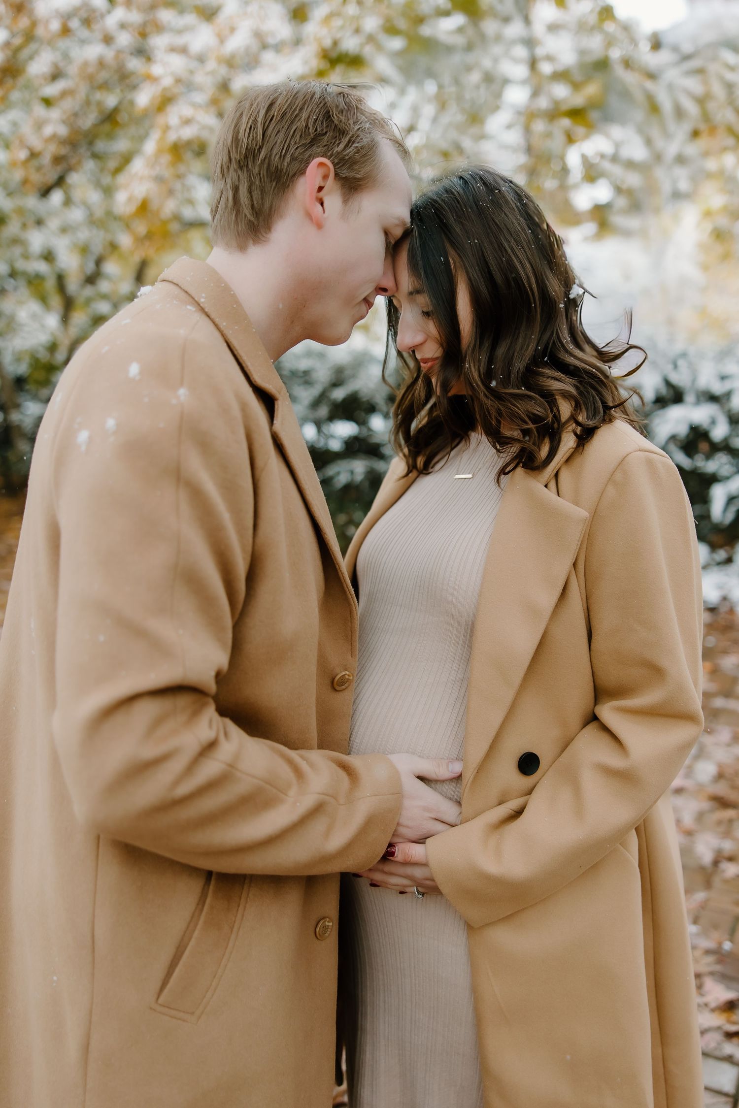 Intimate winter portrait showing two people in matching camel coats embracing.