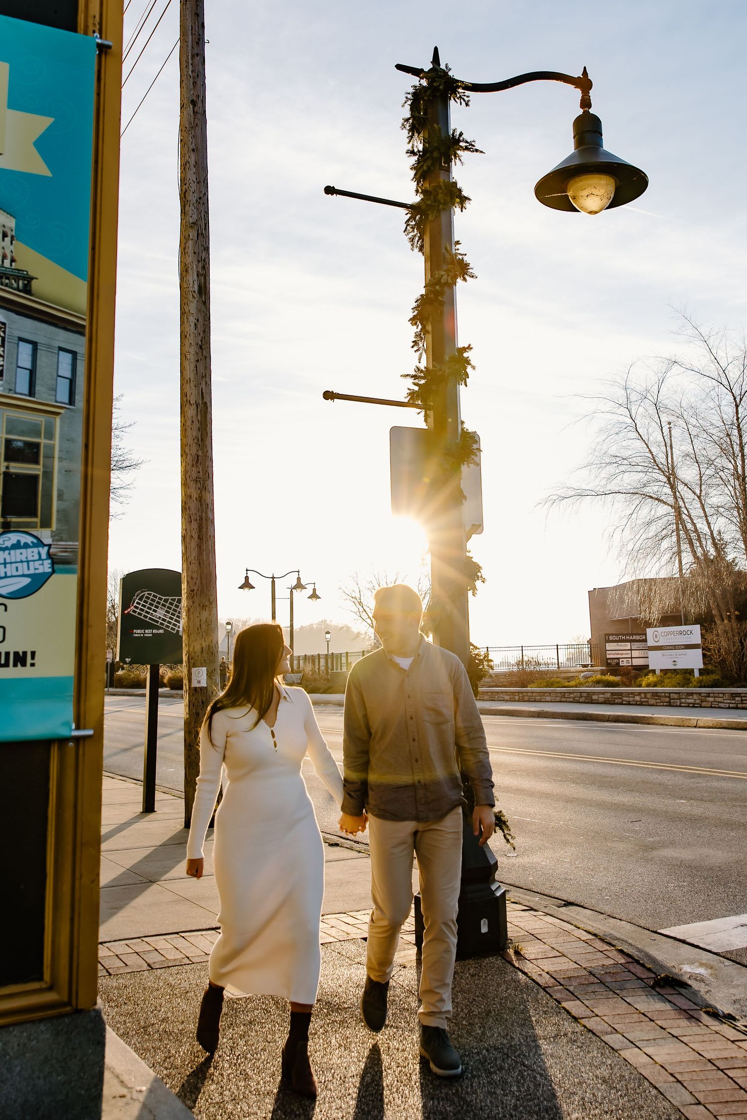 Silhouettes of a couple walking together on a sidewalk during golden hour.