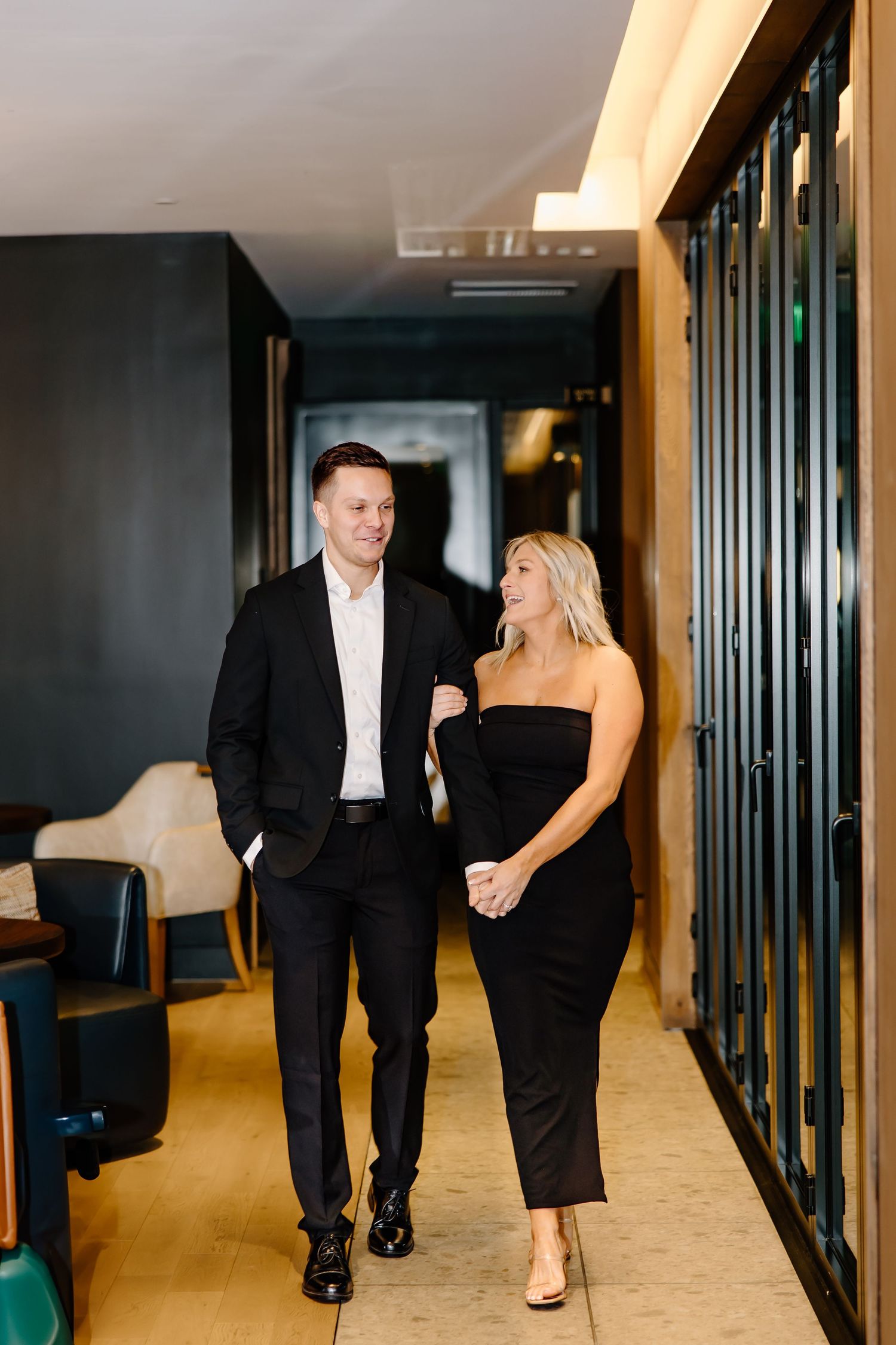 Couple walking and laughing together in a modern hallway.