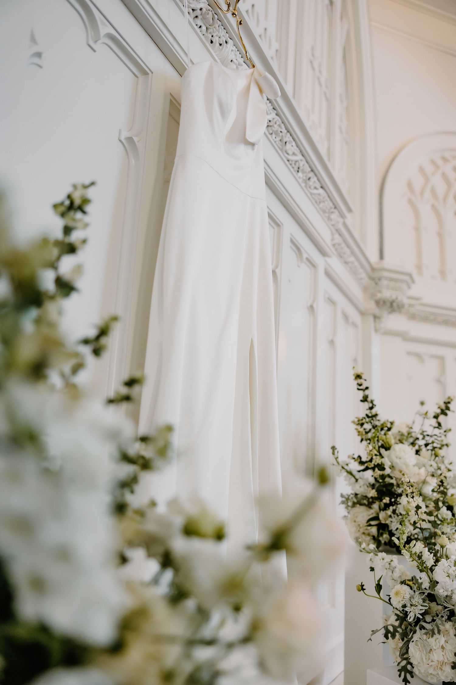 Ornate white architectural details and delicate greenery decorate an elegant wedding venue interior.