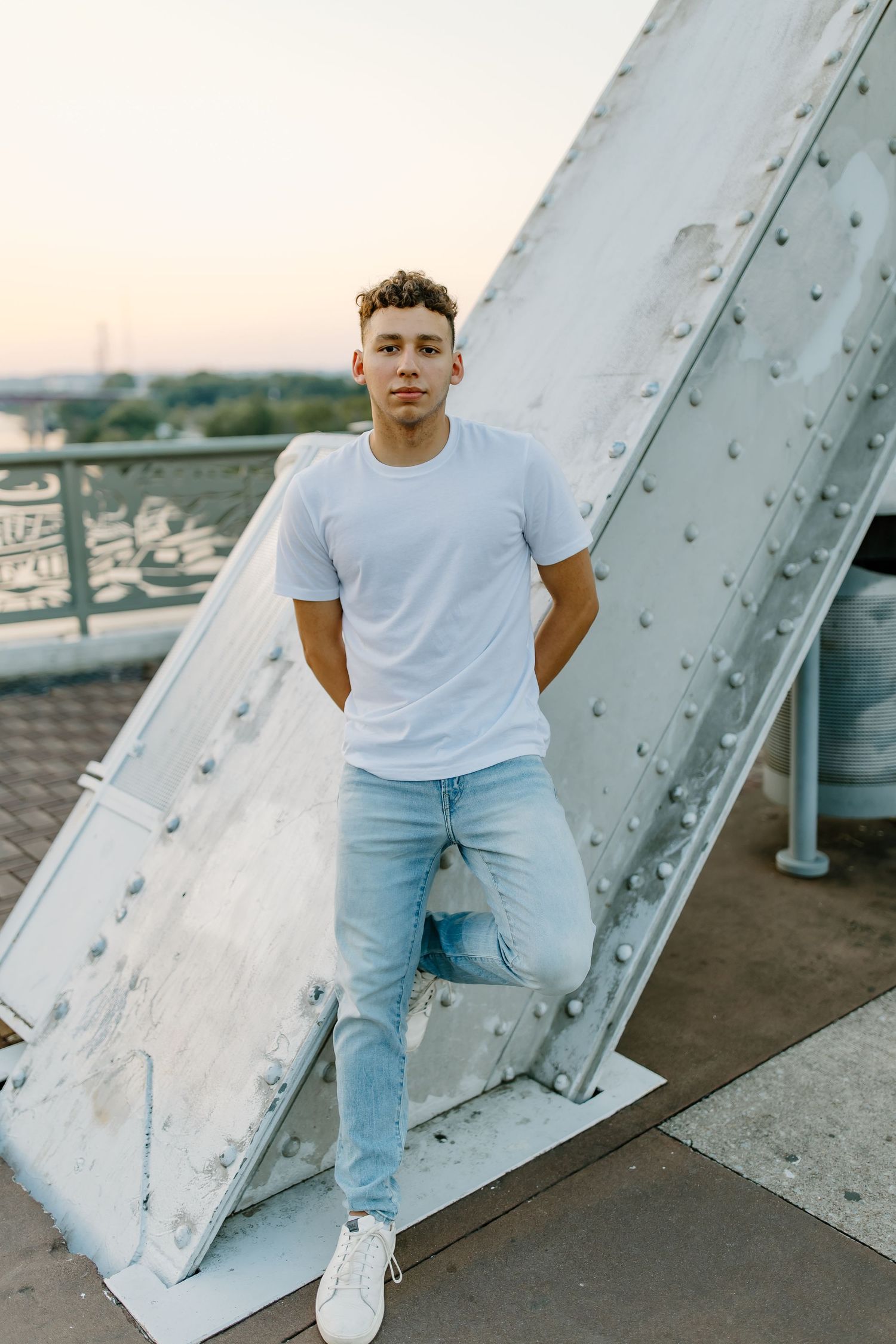 Urban portrait against industrial white metal structure wearing casual attire.