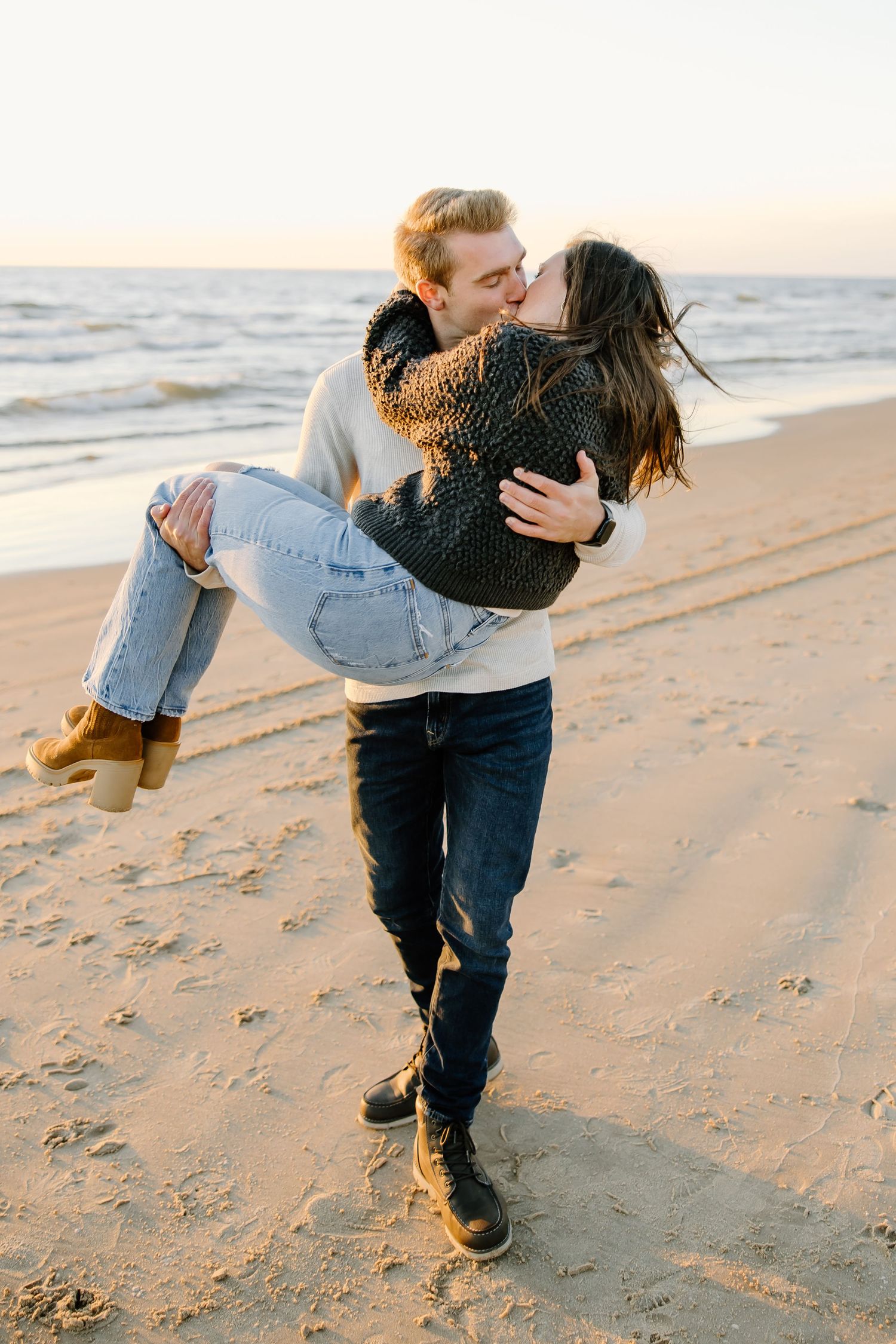 Couple sharing playful moments on beach at sunset.