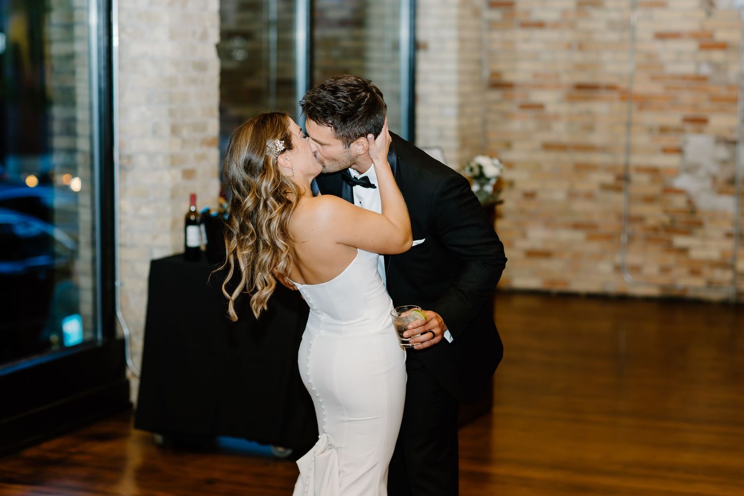 Romantic dancing sequence in a rustic brick-walled venue with string lights.