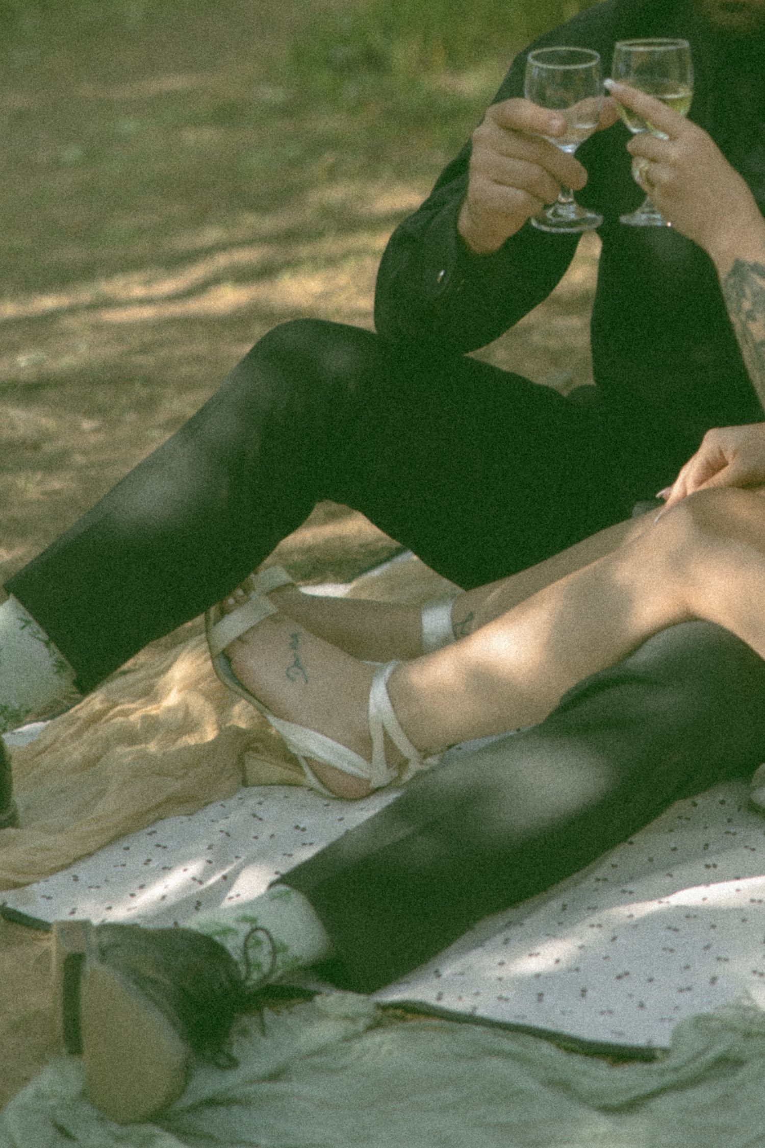 Couple relaxing on blanket in dappled sunlight during outdoor picnic.