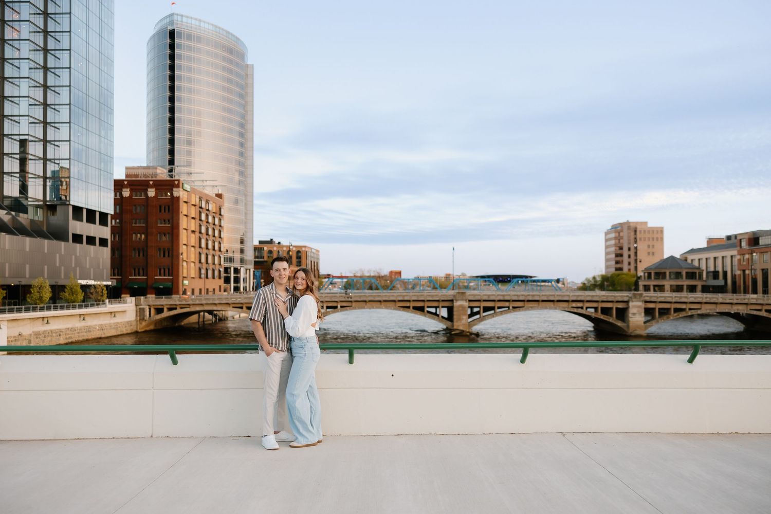 Couple embracing on a rooftop terrace overlooking the Grand River and city skyline in Grand Rapids, Michigan.