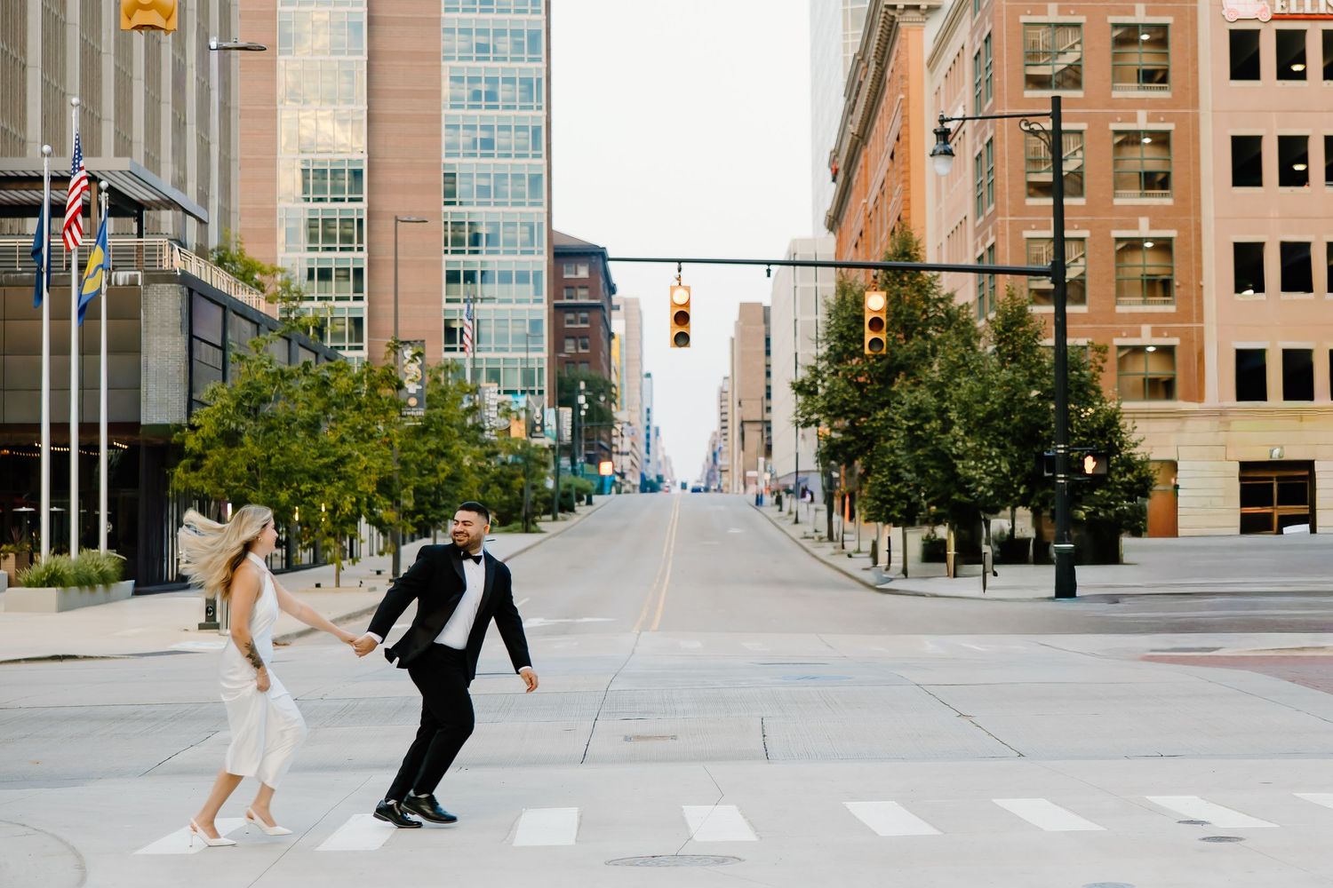 Couple dancing playfully in empty city street intersection.