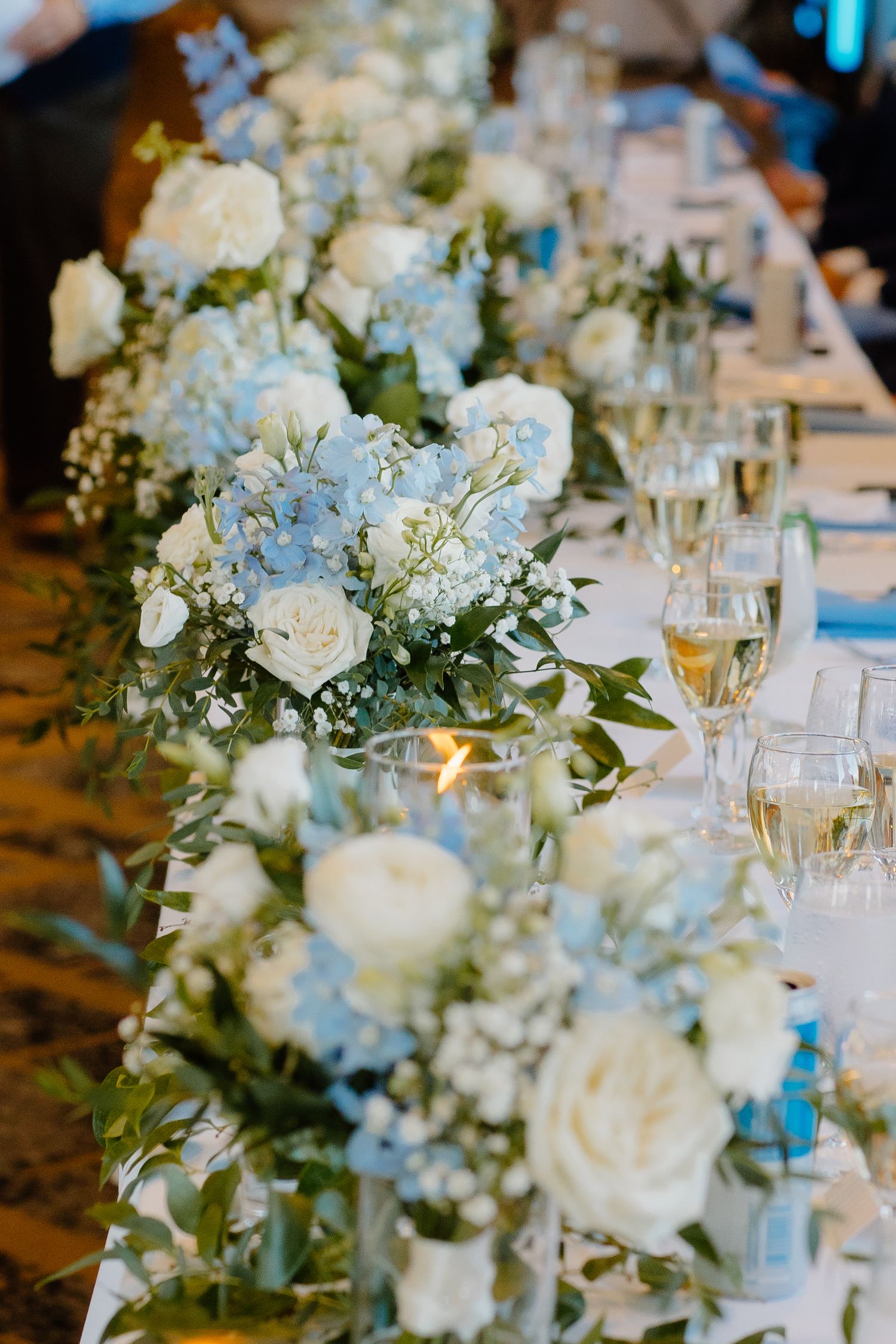 Elegant wedding reception table decorated with white floral centerpieces and candlelight.