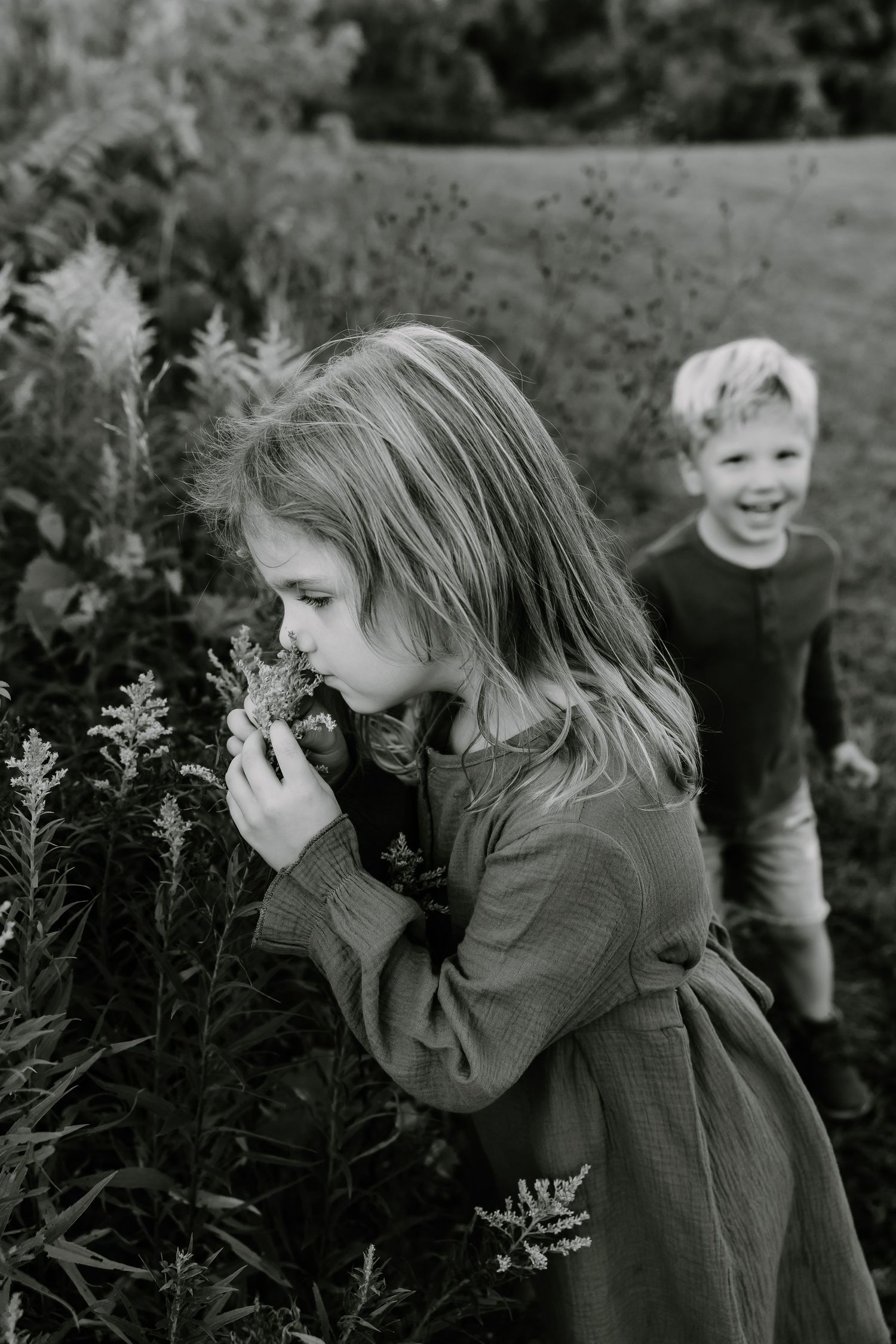 Child exploring nature and smelling flowers in a garden setting.