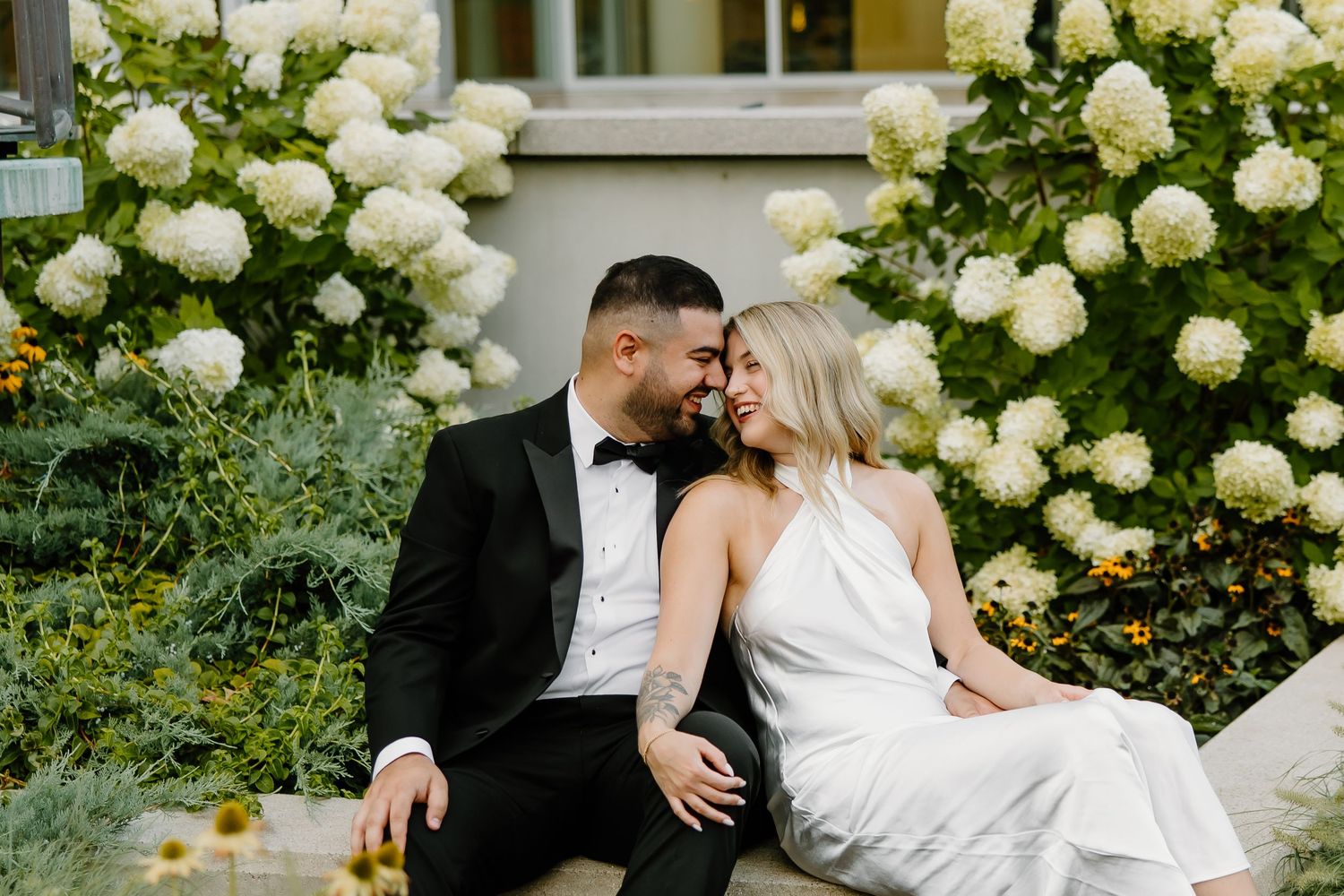Romantic wedding portraits among blooming white hydrangea bushes.