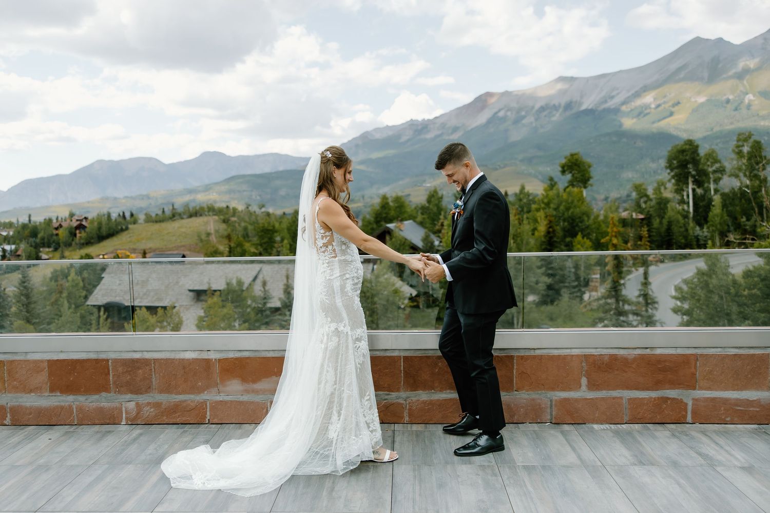A couple exchanges wedding vows on an outdoor terrace with majestic mountain views.