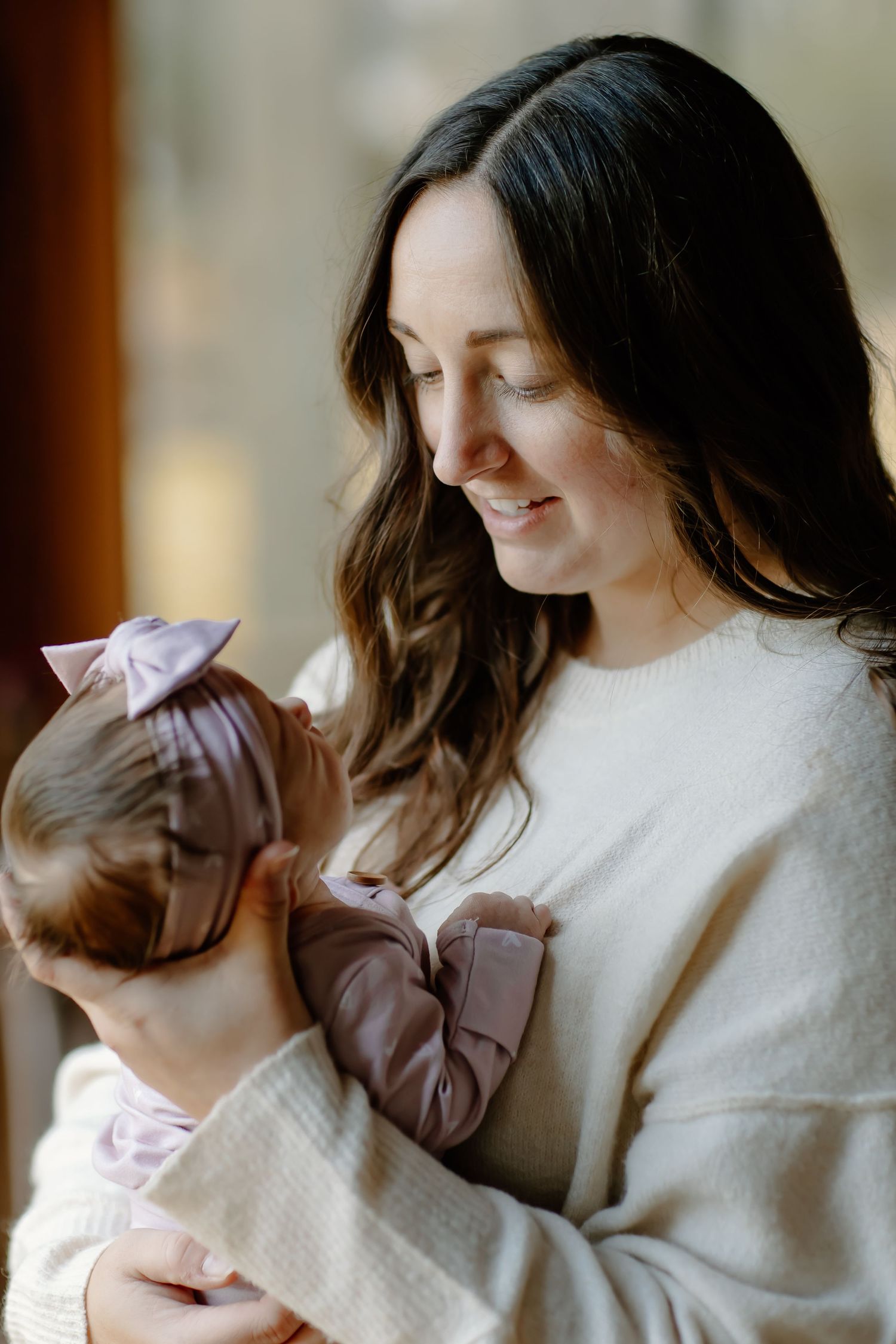 A gentle moment between parent and baby wearing matching cream colored sweaters.