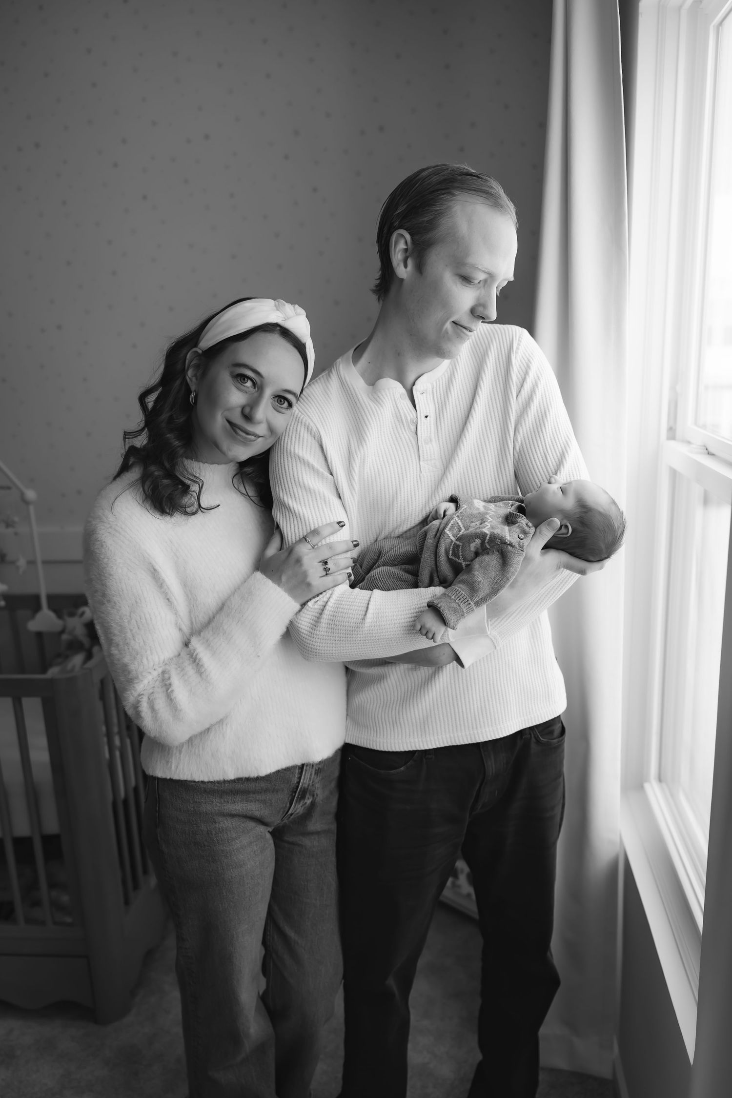 An intimate family moment captured in black and white by a bright window.