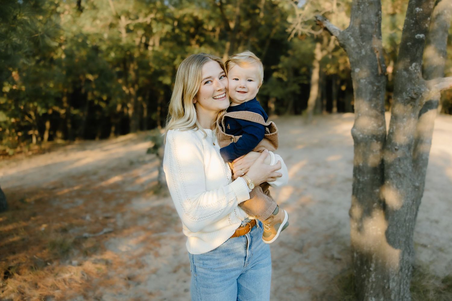 Family portrait session in natural outdoor setting with golden sunlight filtering through trees.