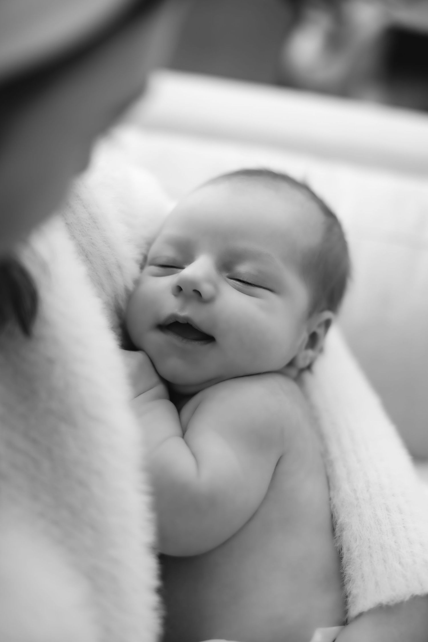 Black and white portraits of a sleeping newborn wrapped in white blankets.