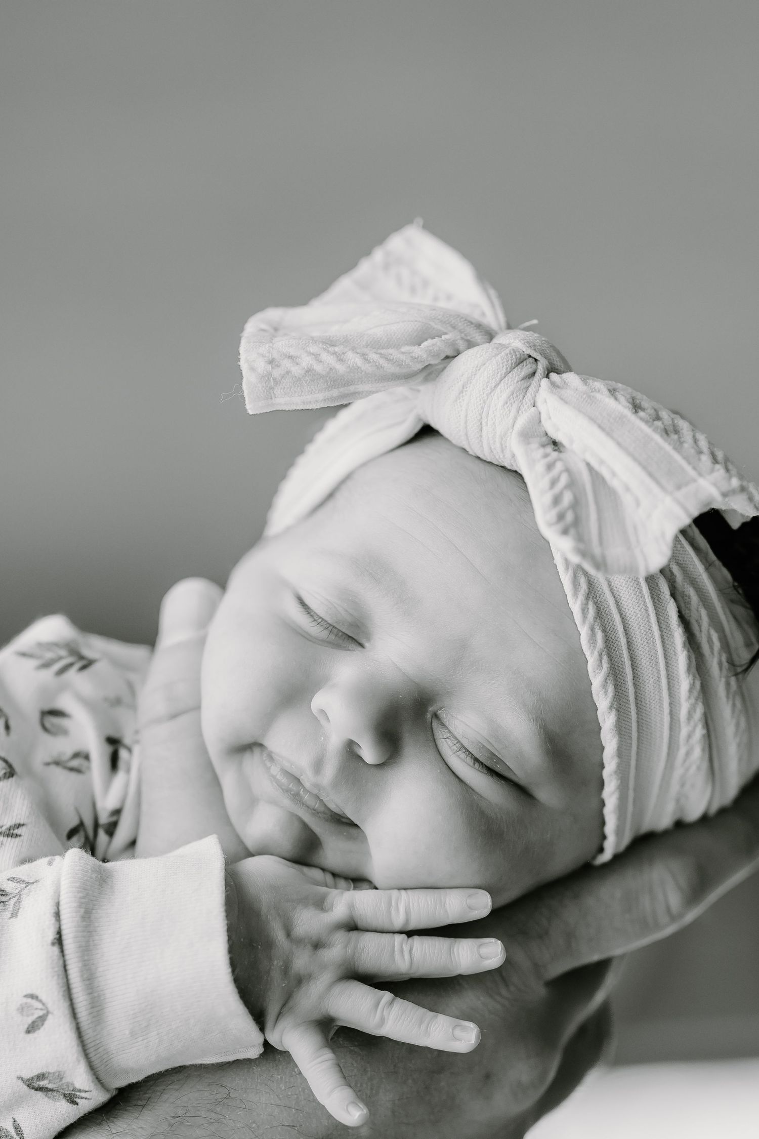 Black and white portrait series of a sleeping newborn with white headband.