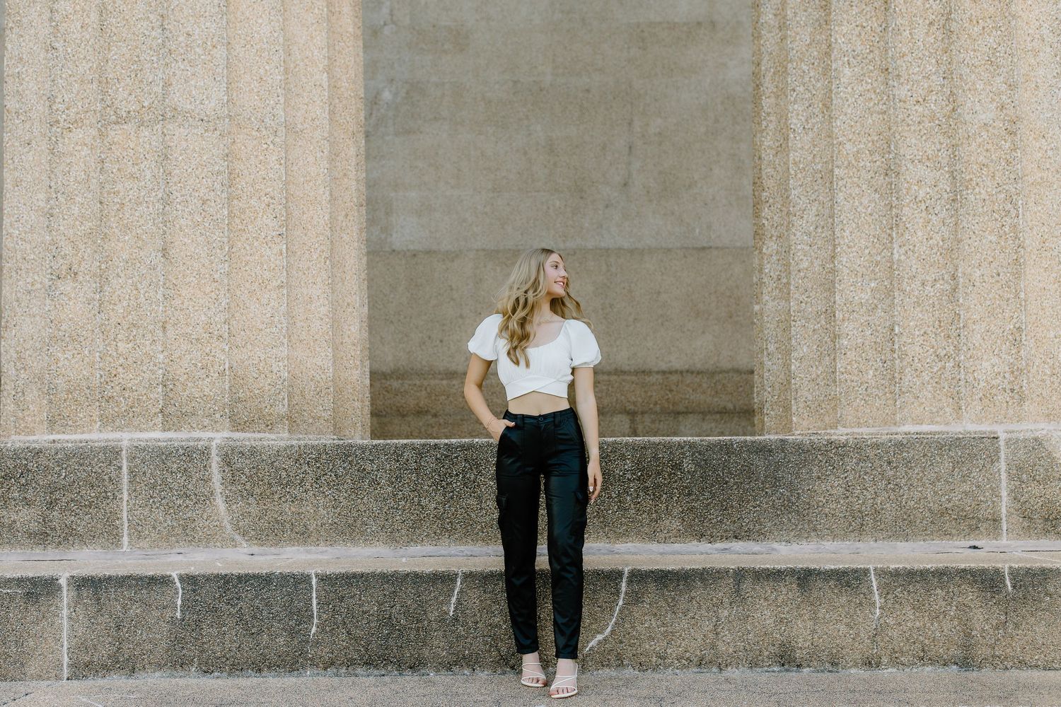 A person in black pants and white top stands against a stone wall in multiple poses for a photo series.