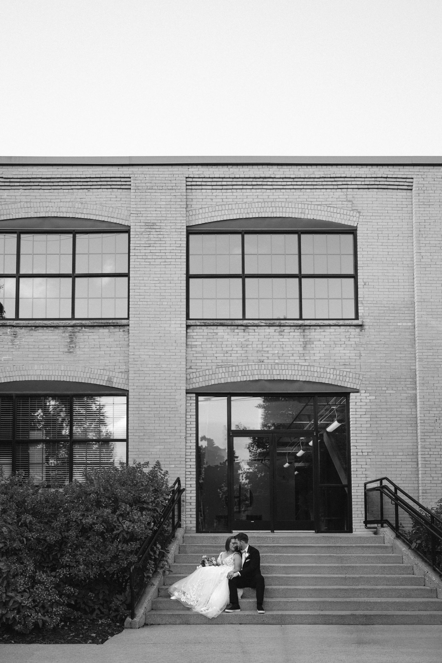 Modern brick building exterior with large windows and steps where a wedding photo session takes place.
