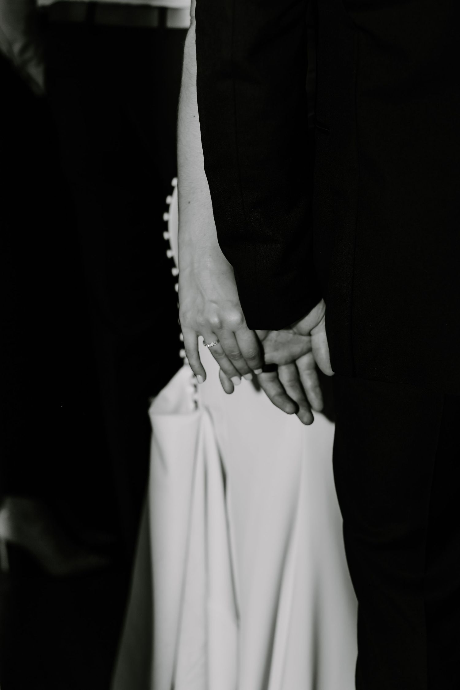 Close-up detail shot of a white wedding dress being held.