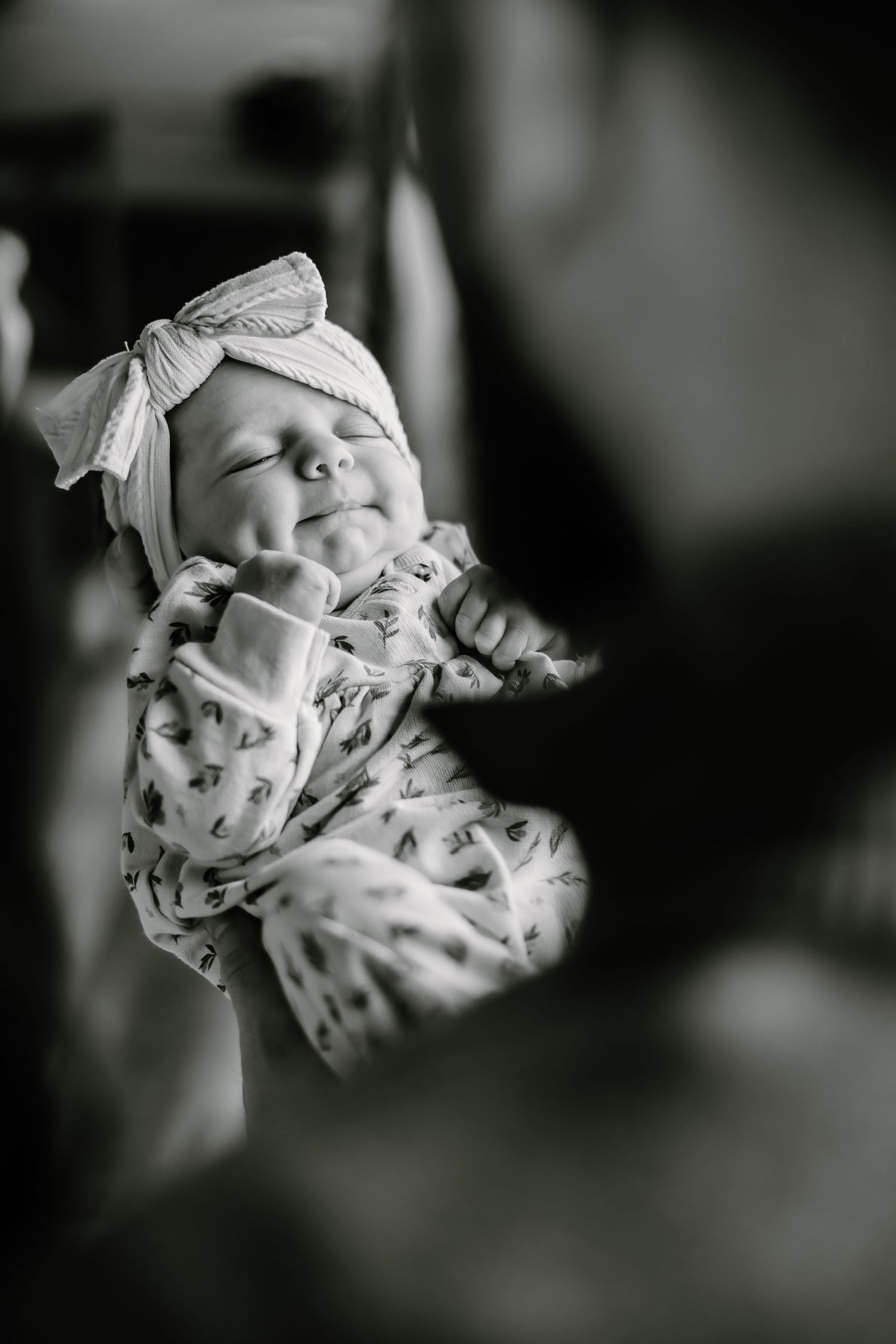 Artistic black and white portrait of a sleeping newborn with bow detail.