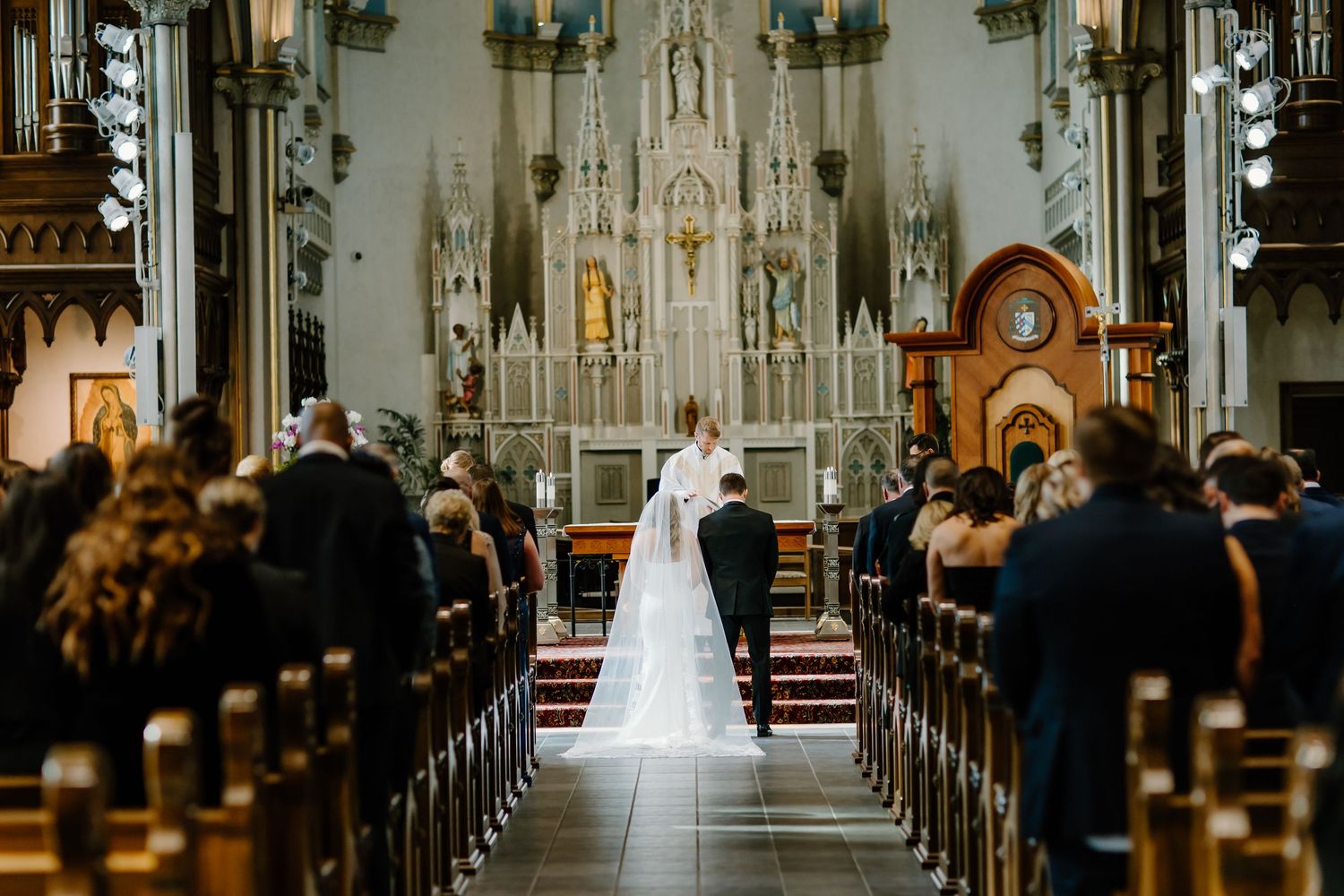 A stunning Catholic church interior with vaulted ceilings and ornate Gothic architecture during a wedding ceremony.