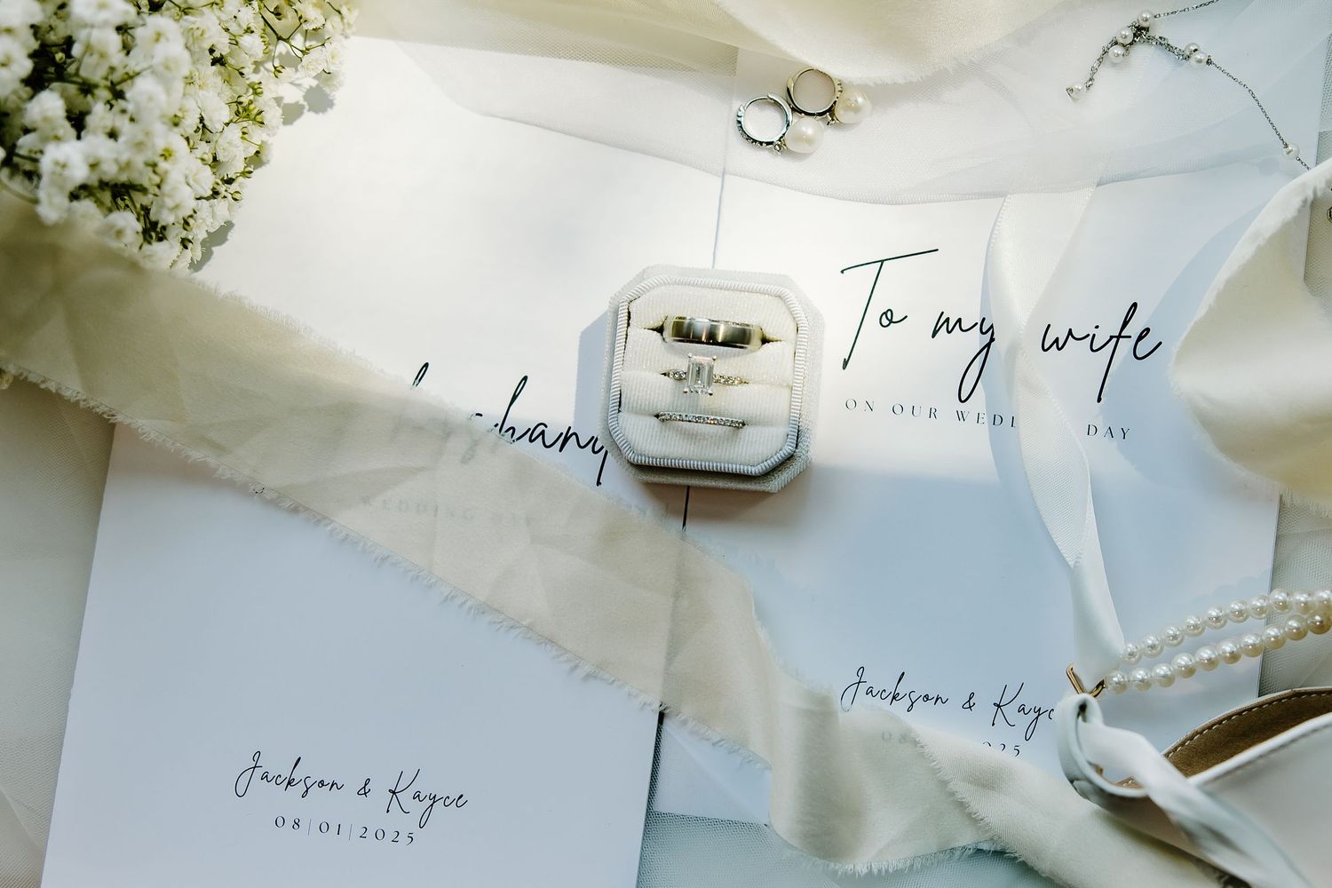 Elegant wedding stationery with handwritten calligraphy and floral details arranged on a white surface.