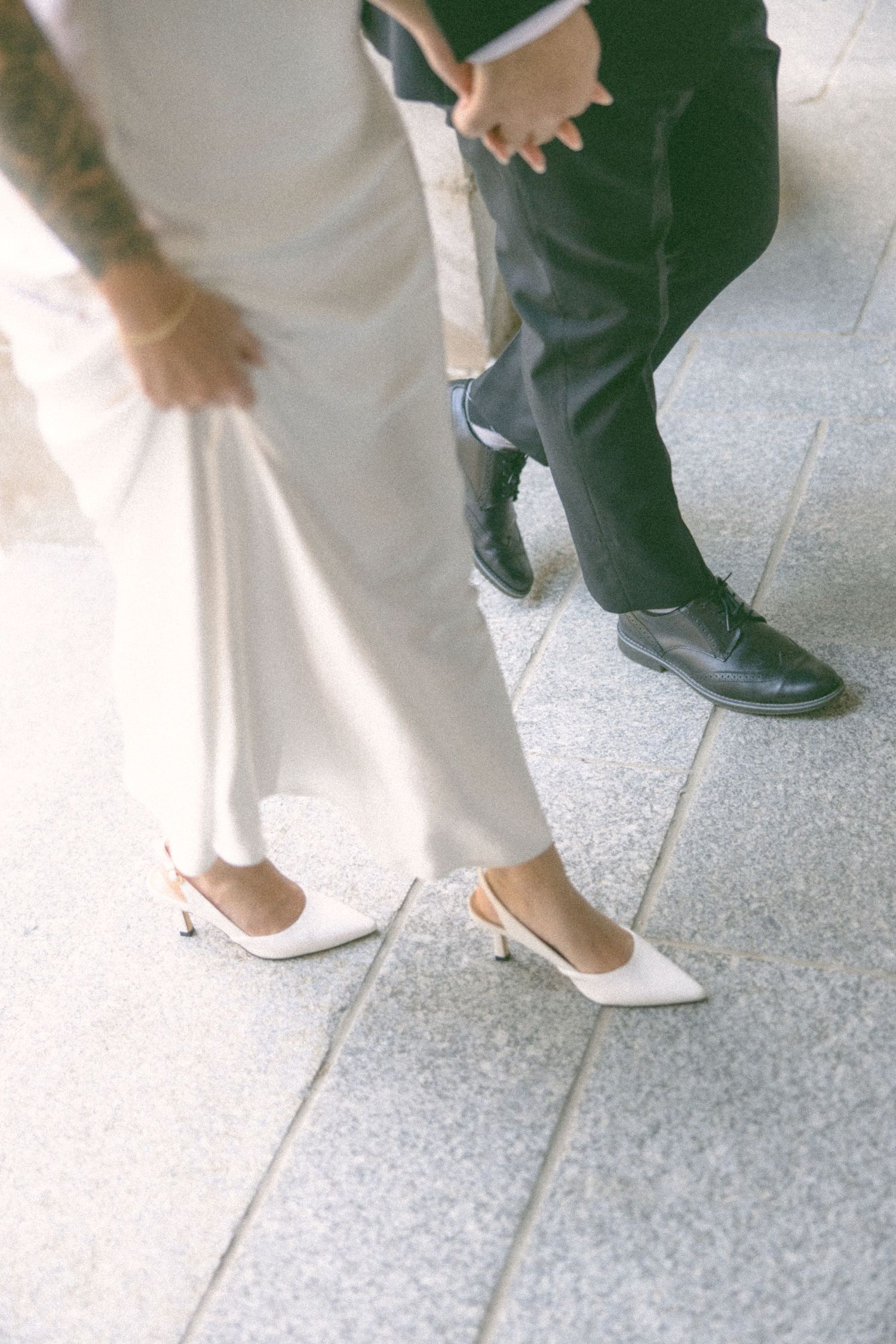 Close-up of formal shoes and dress hem on tiled floor.
