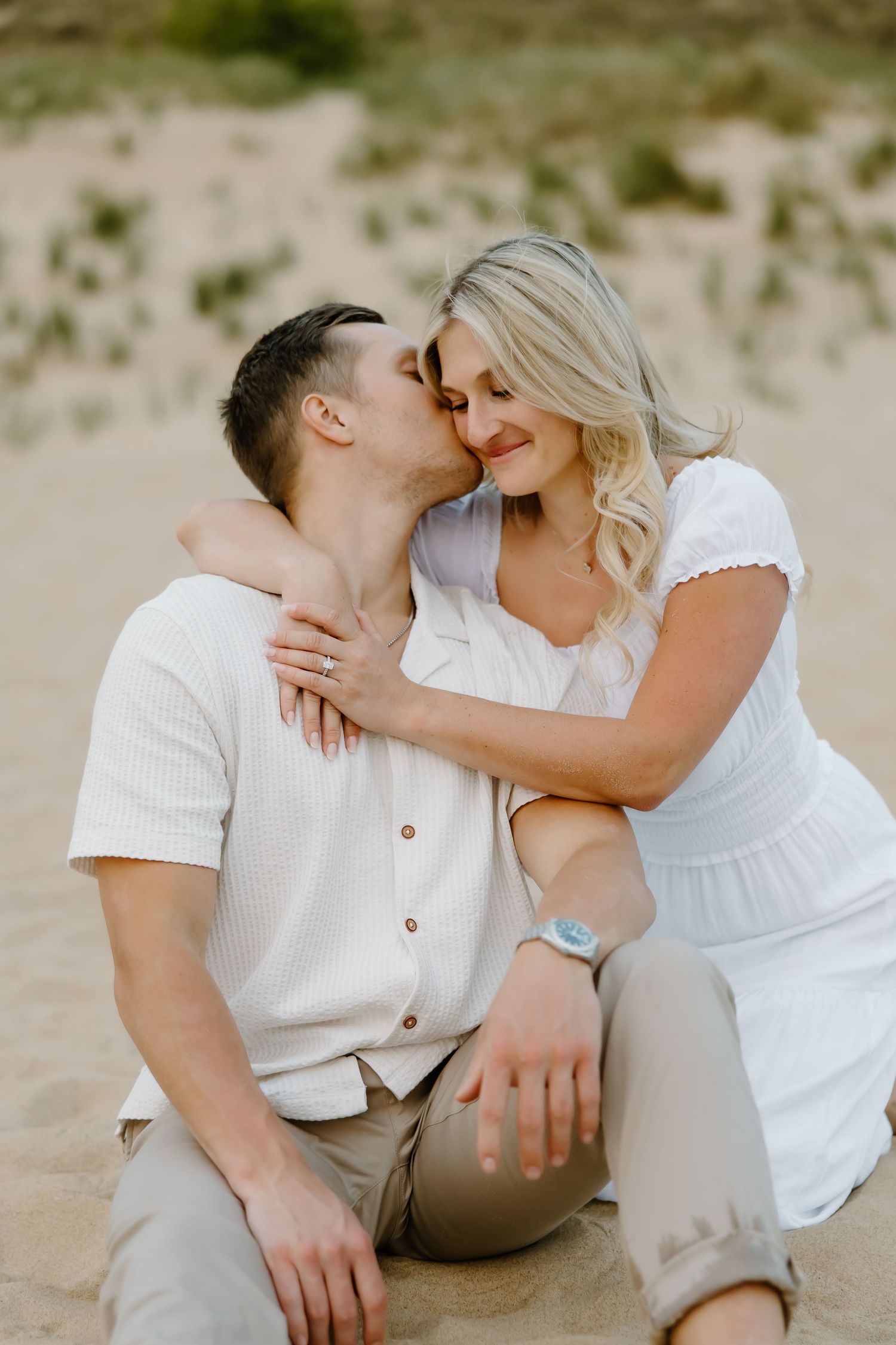 Intimate beach engagement photo with couple in white and khaki.