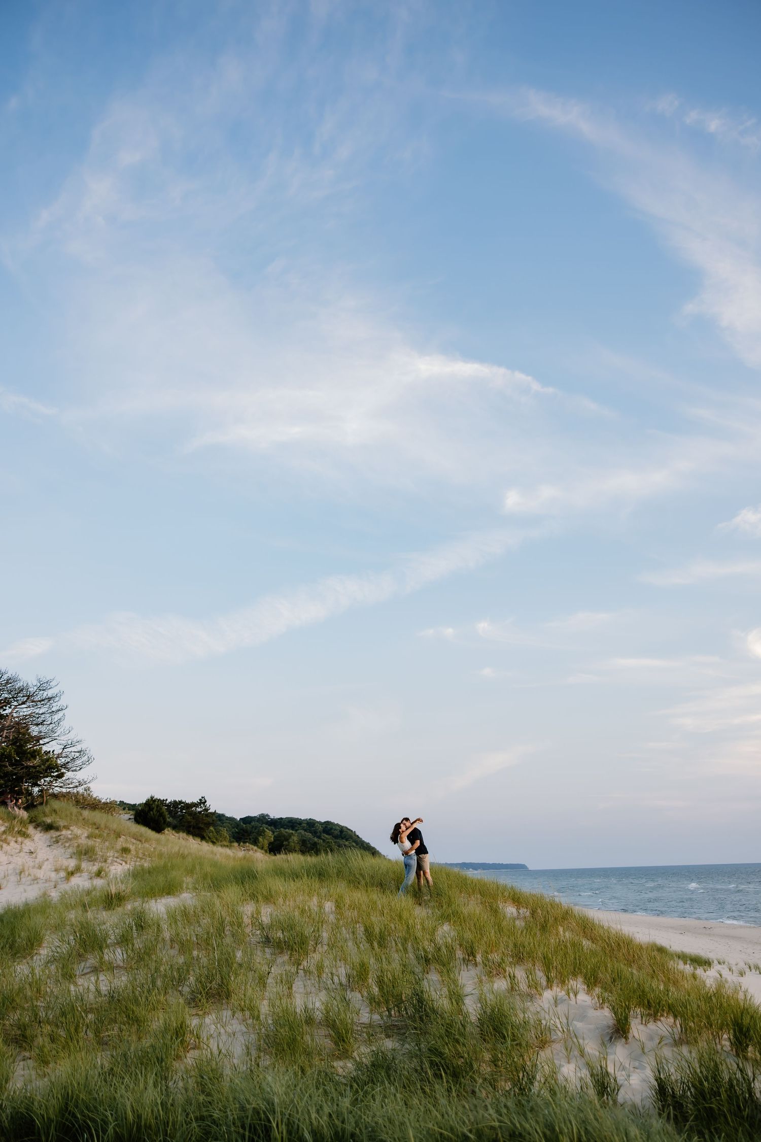 Beautiful beach landscape with rolling dunes and distant figures against blue sky.