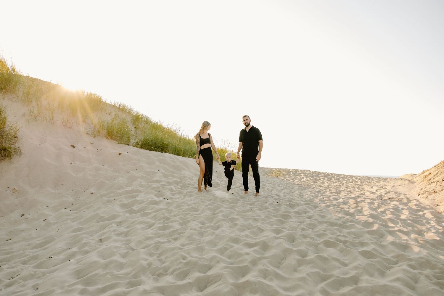 Group walking along sandy beach dunes at sunset.