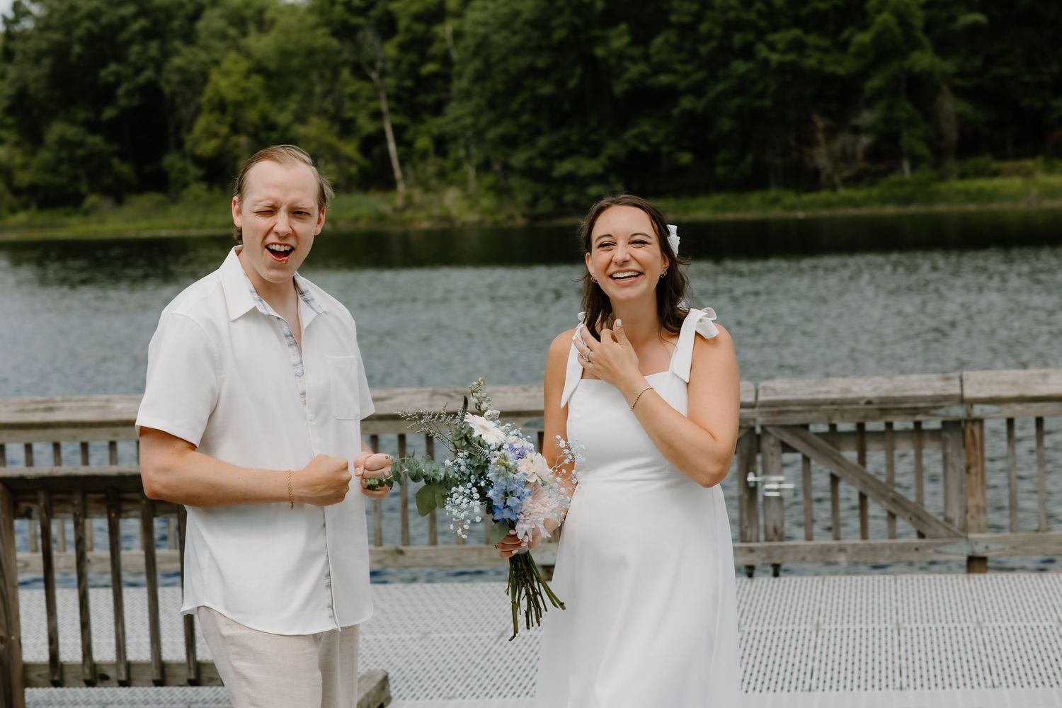 Romantic outdoor photo session by a lake with a wooden deck and lush greenery.