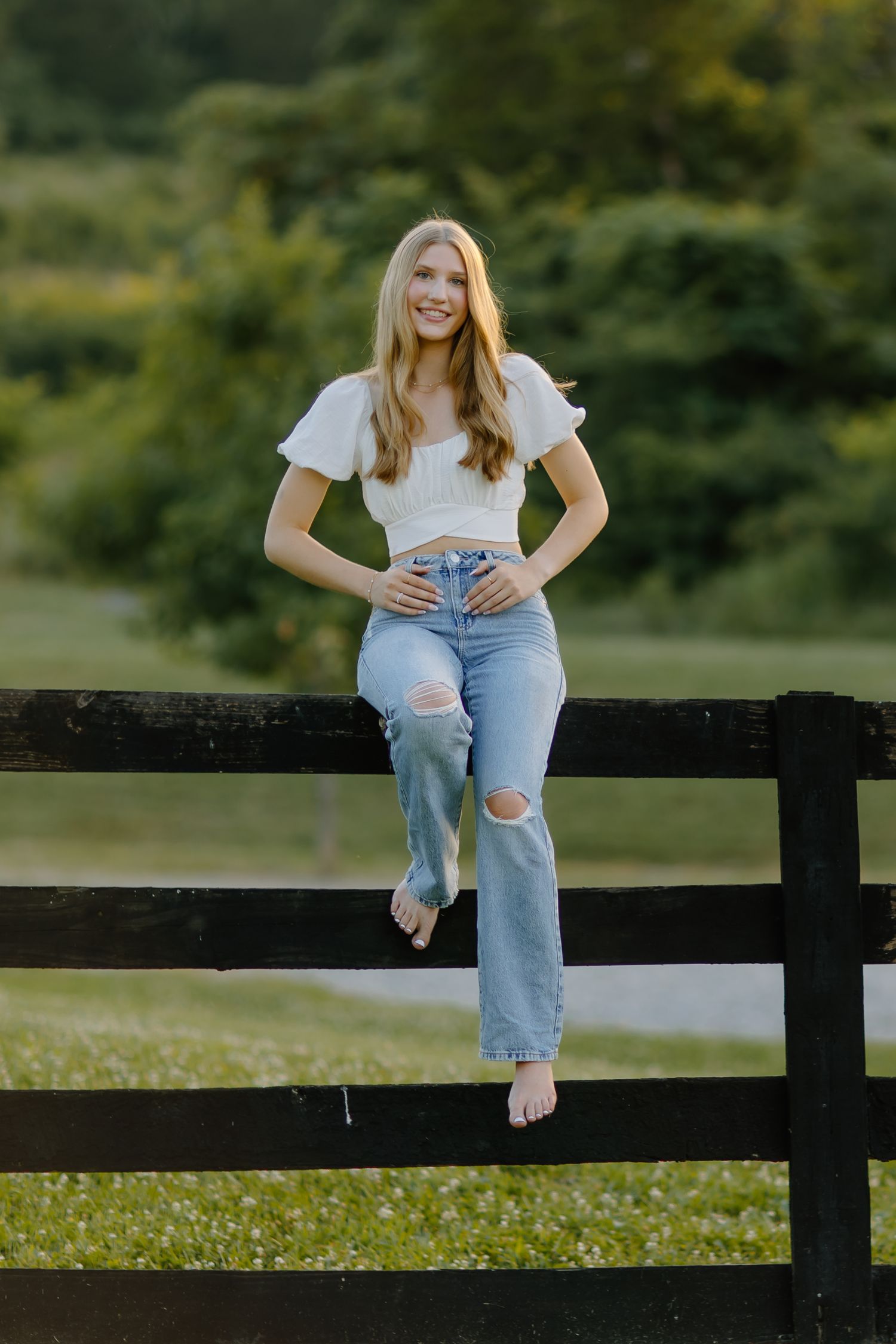 Casual portrait session at a rustic black fence in a countryside setting.