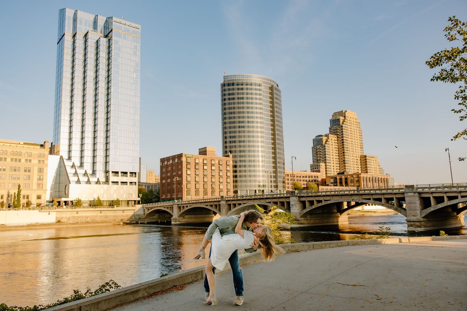 Urban waterfront panorama with city skyline and river during sunset.